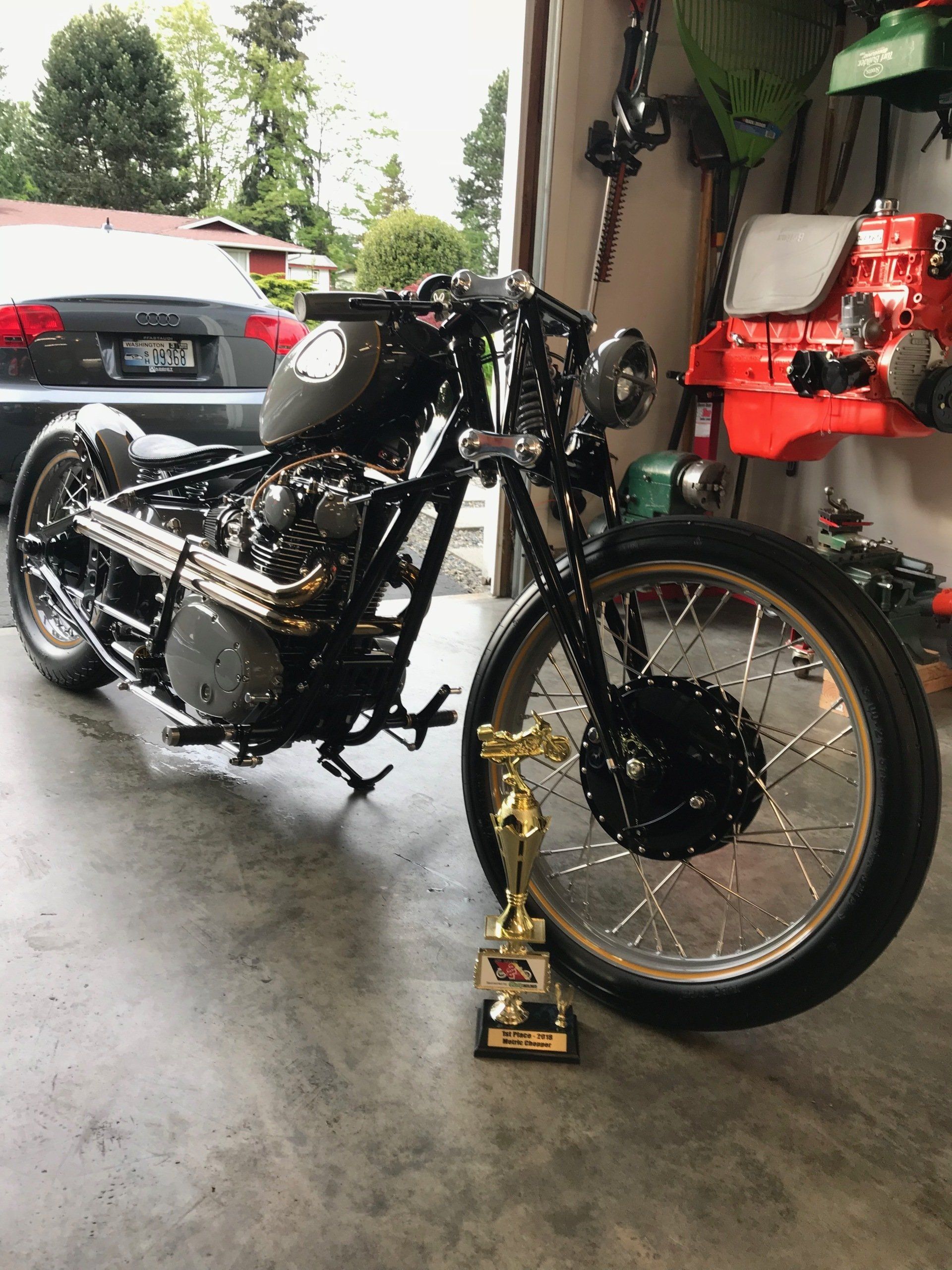 A motorcycle is parked in a garage next to a trophy.