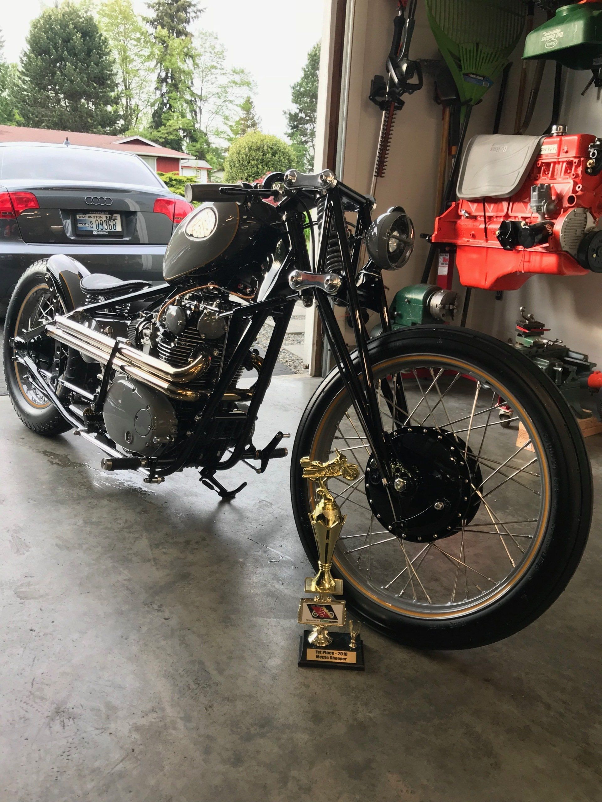 A motorcycle is parked in a garage next to a trophy.