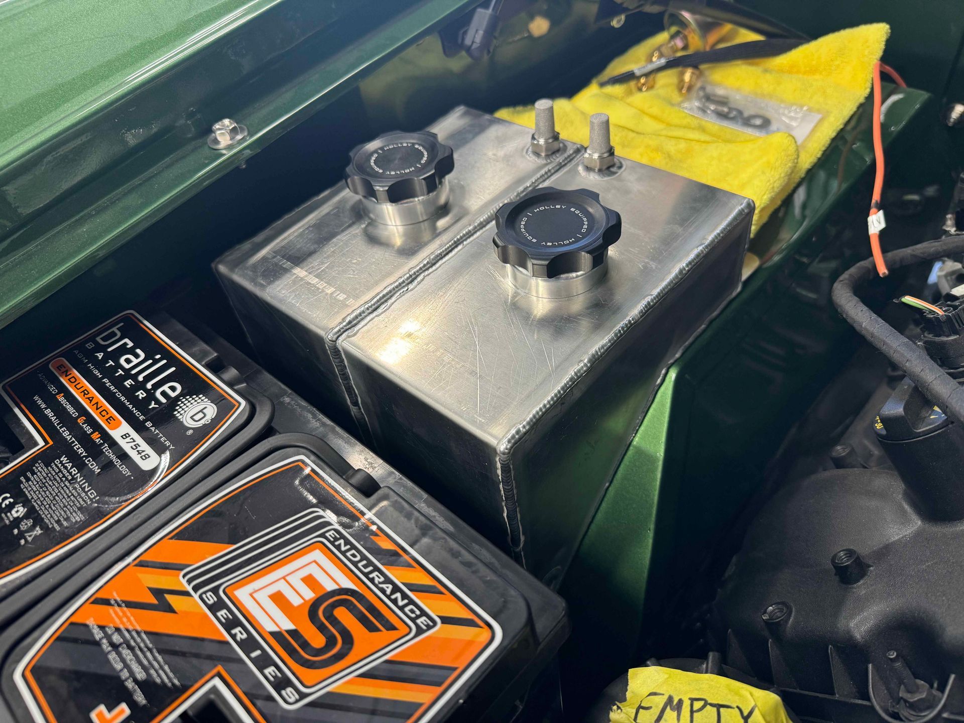 Two batteries are sitting under the hood of a car