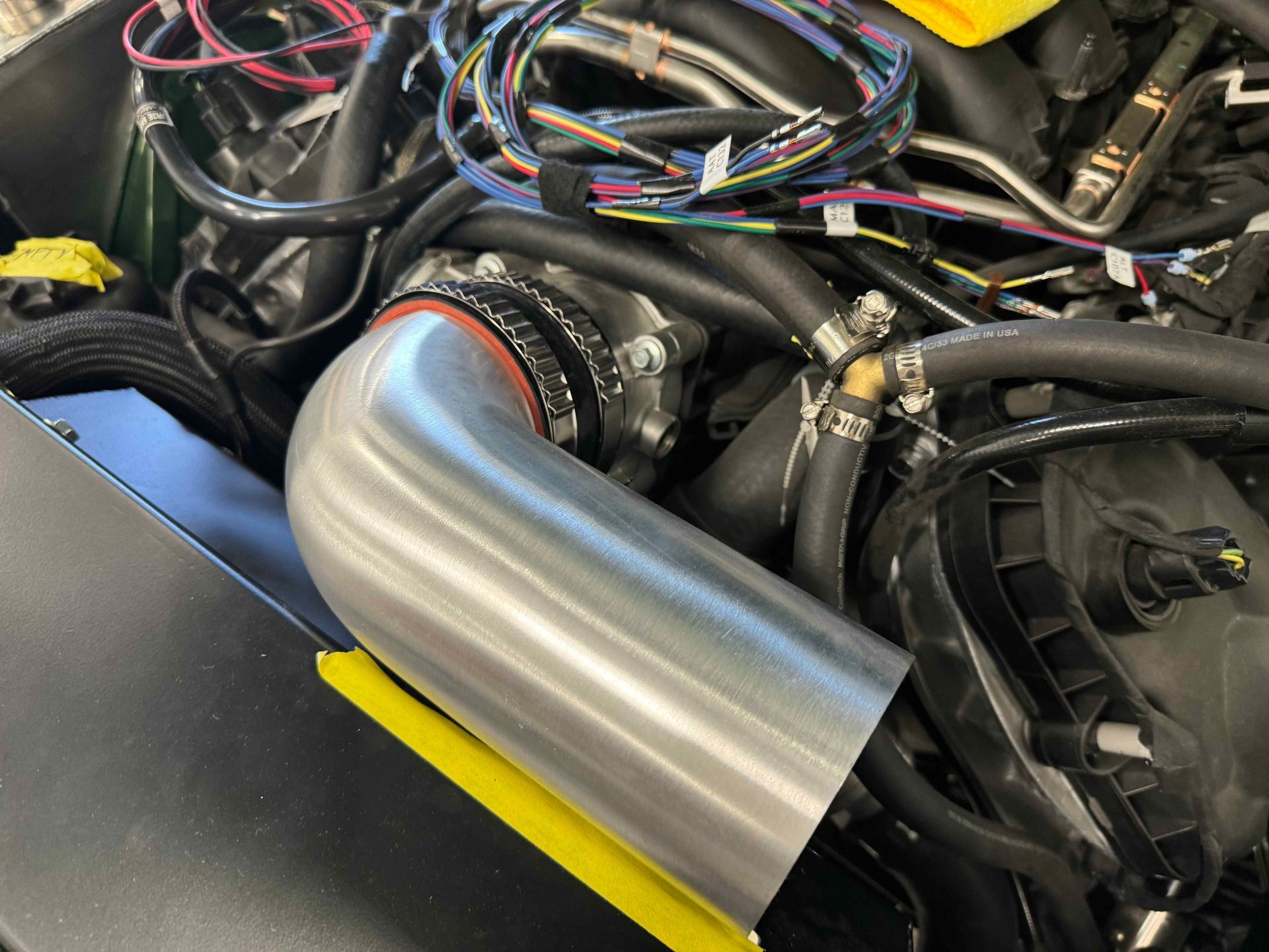 A close up of a car engine with a hose attached to it