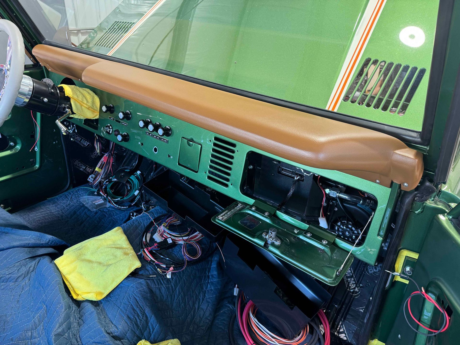 A green car with a brown dashboard is being worked on