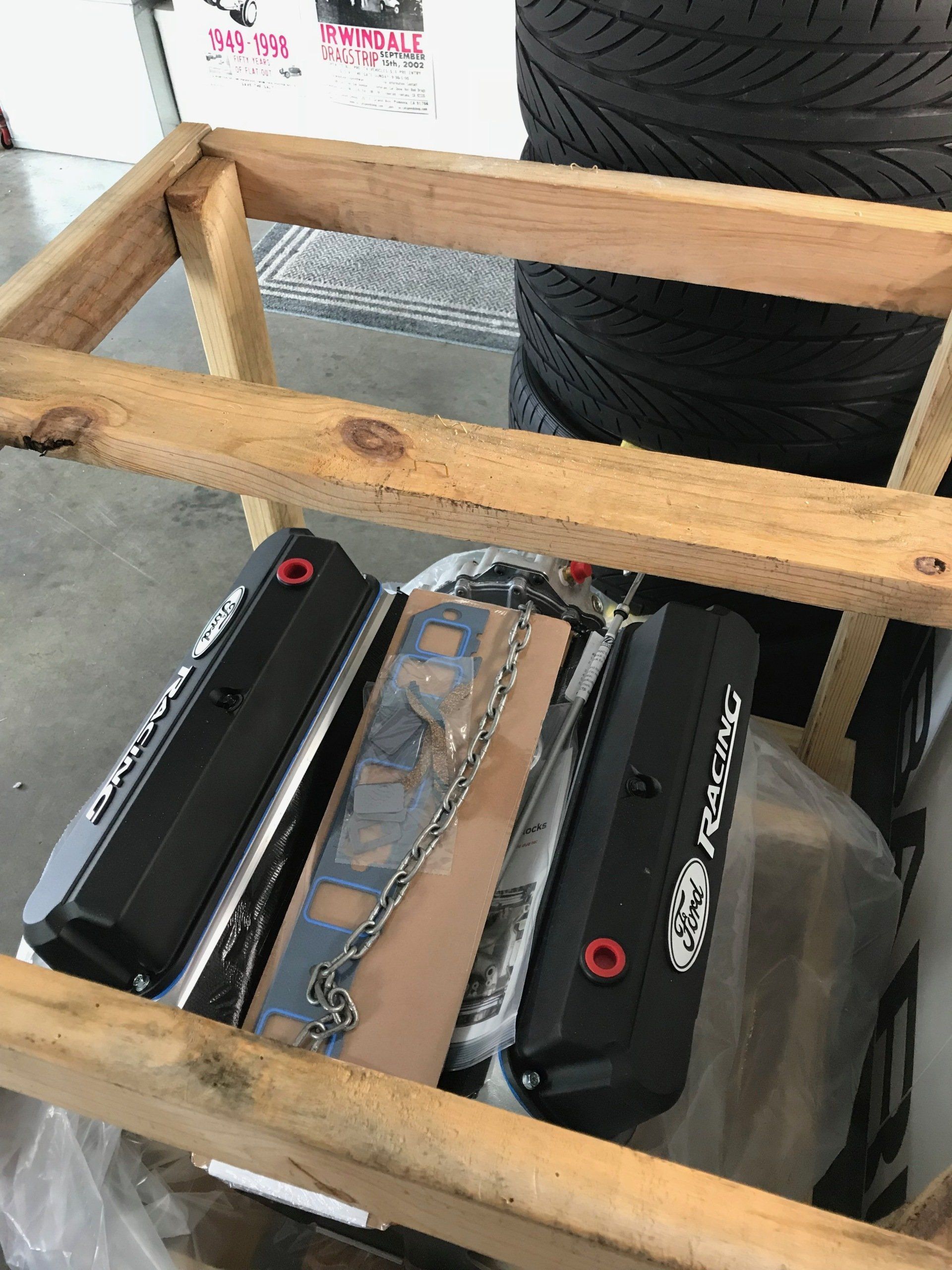 A wooden crate filled with engine parts and tires.