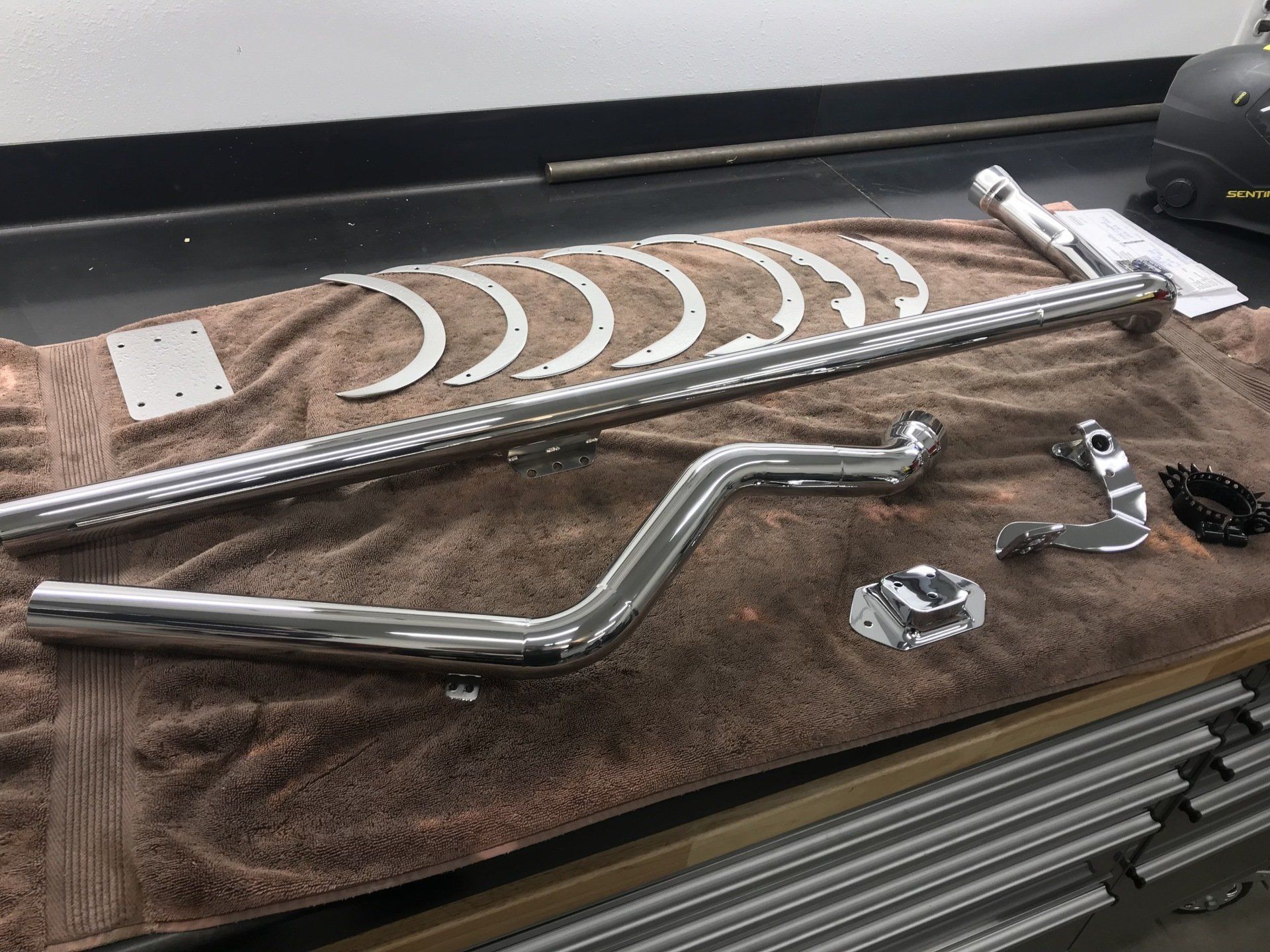A bunch of chrome parts are laying on a towel on a table.
