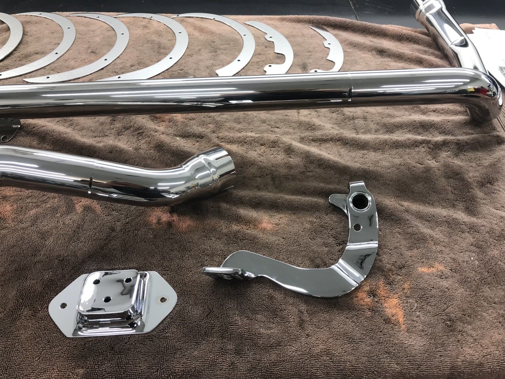 A bunch of chrome parts are laying on a brown towel.