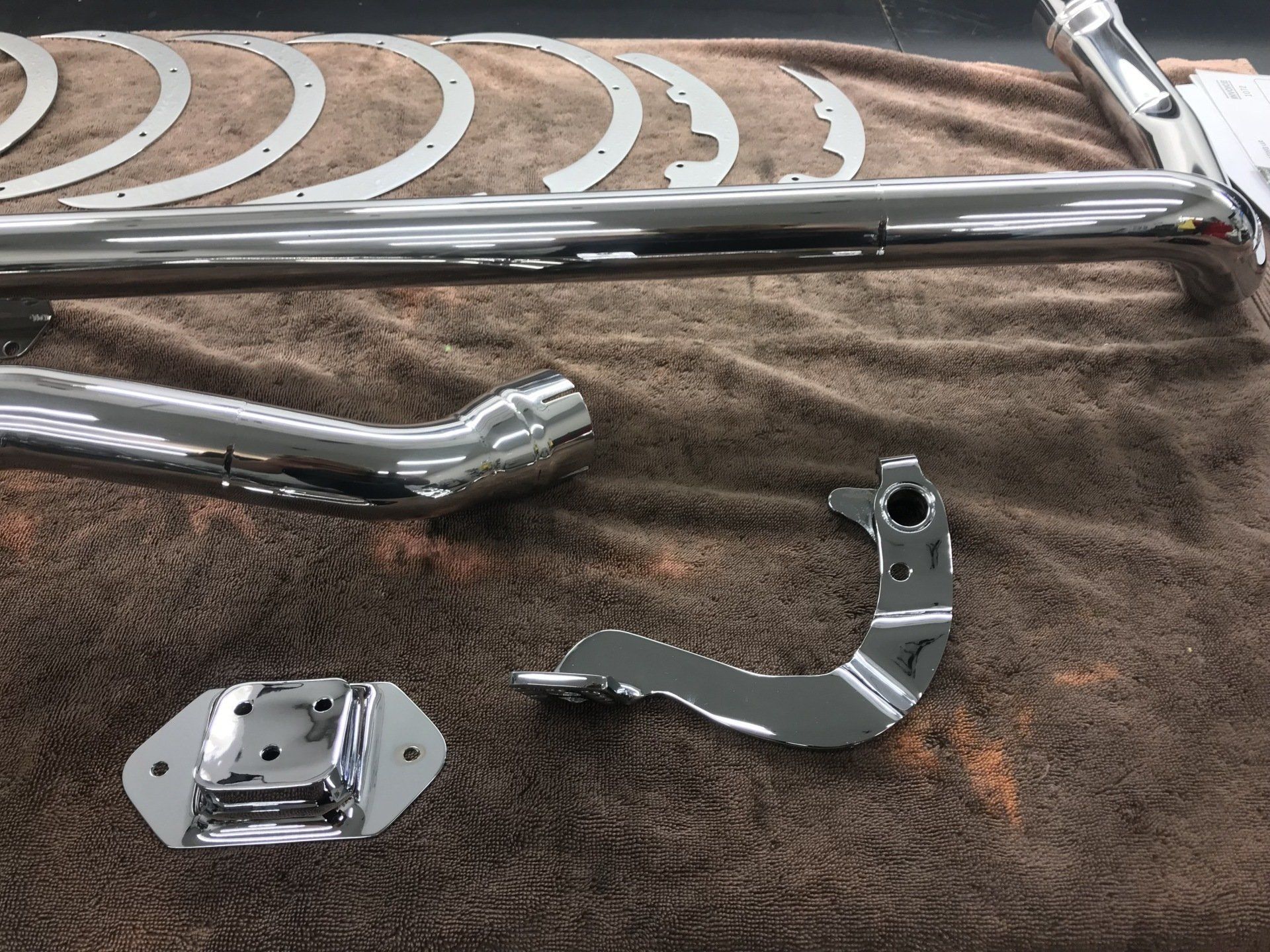 A bunch of chrome parts are laying on a brown towel.