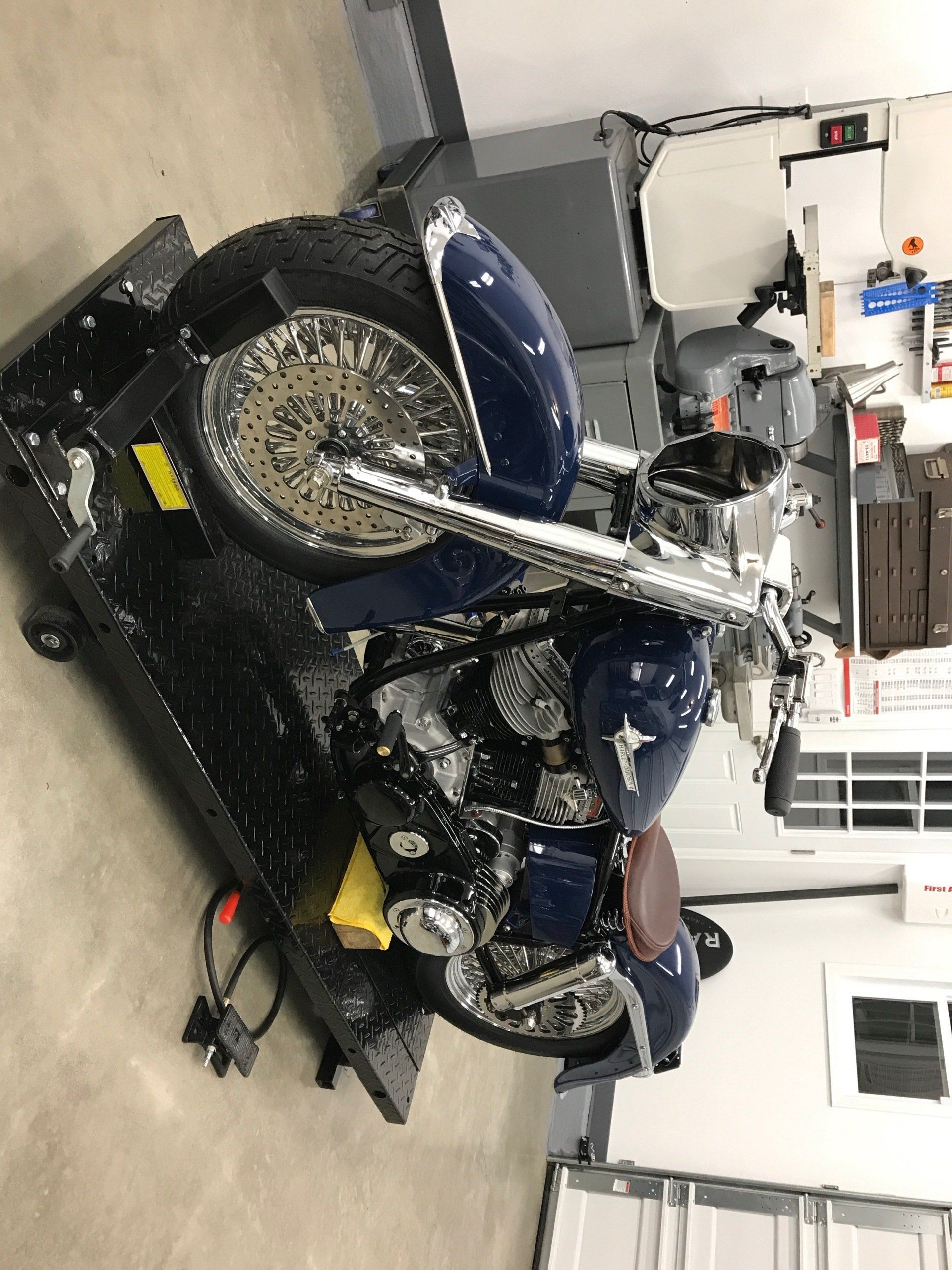 A blue motorcycle is sitting on a lift in a garage.