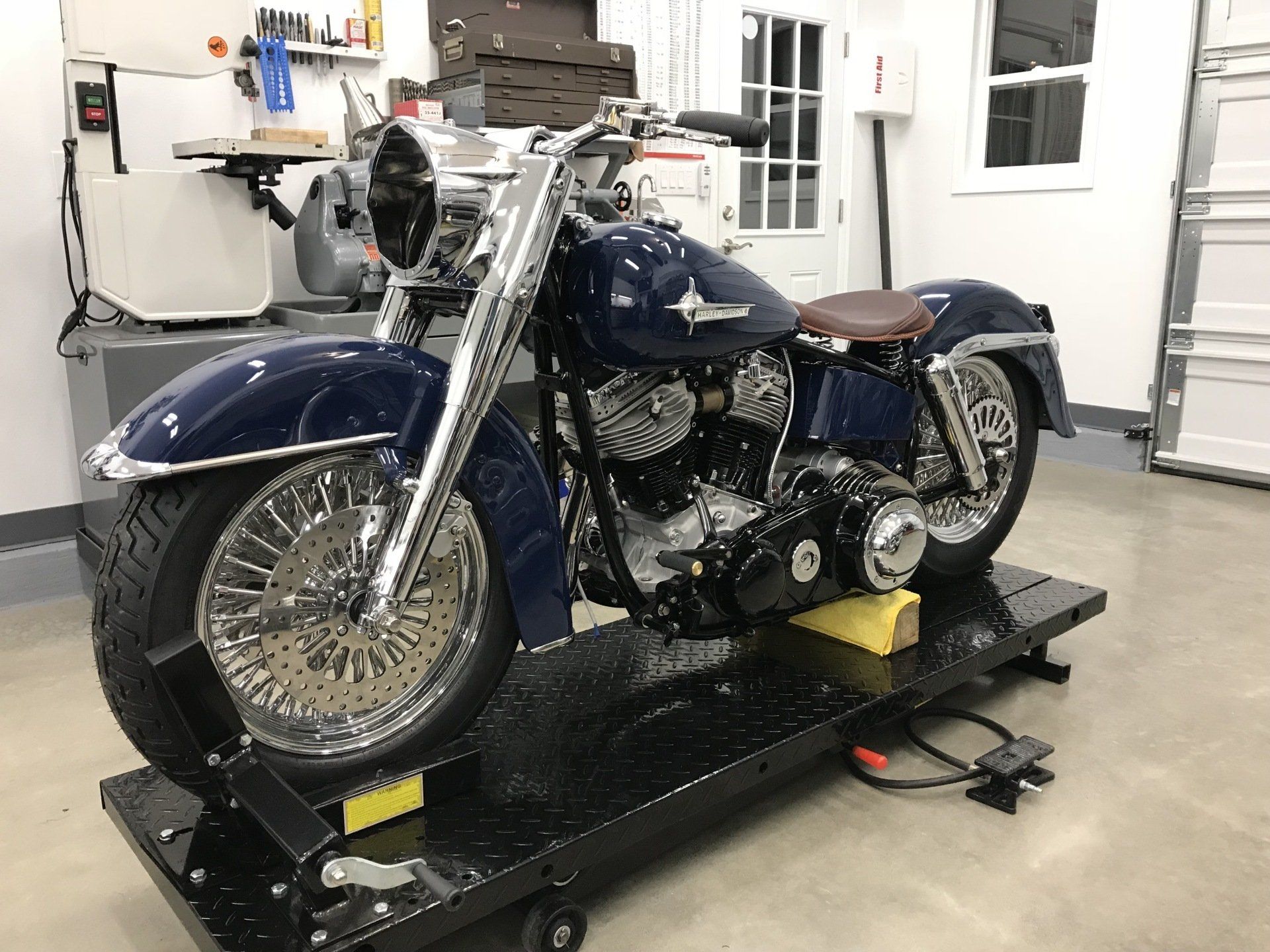 A blue motorcycle is sitting on a lift in a garage.