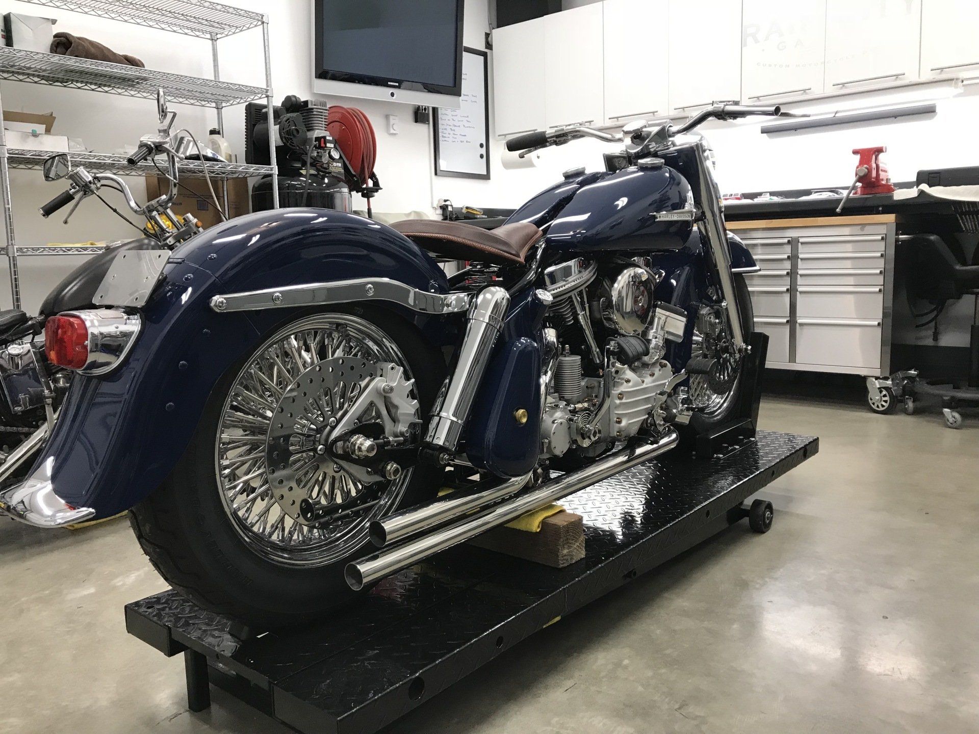 A blue motorcycle is sitting on a lift in a garage.