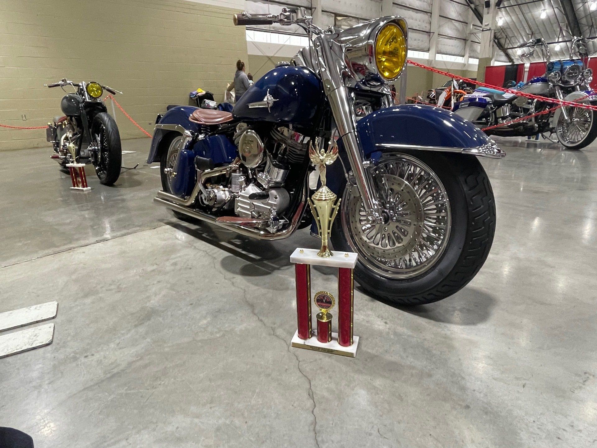 A blue motorcycle is parked next to a trophy on the floor.