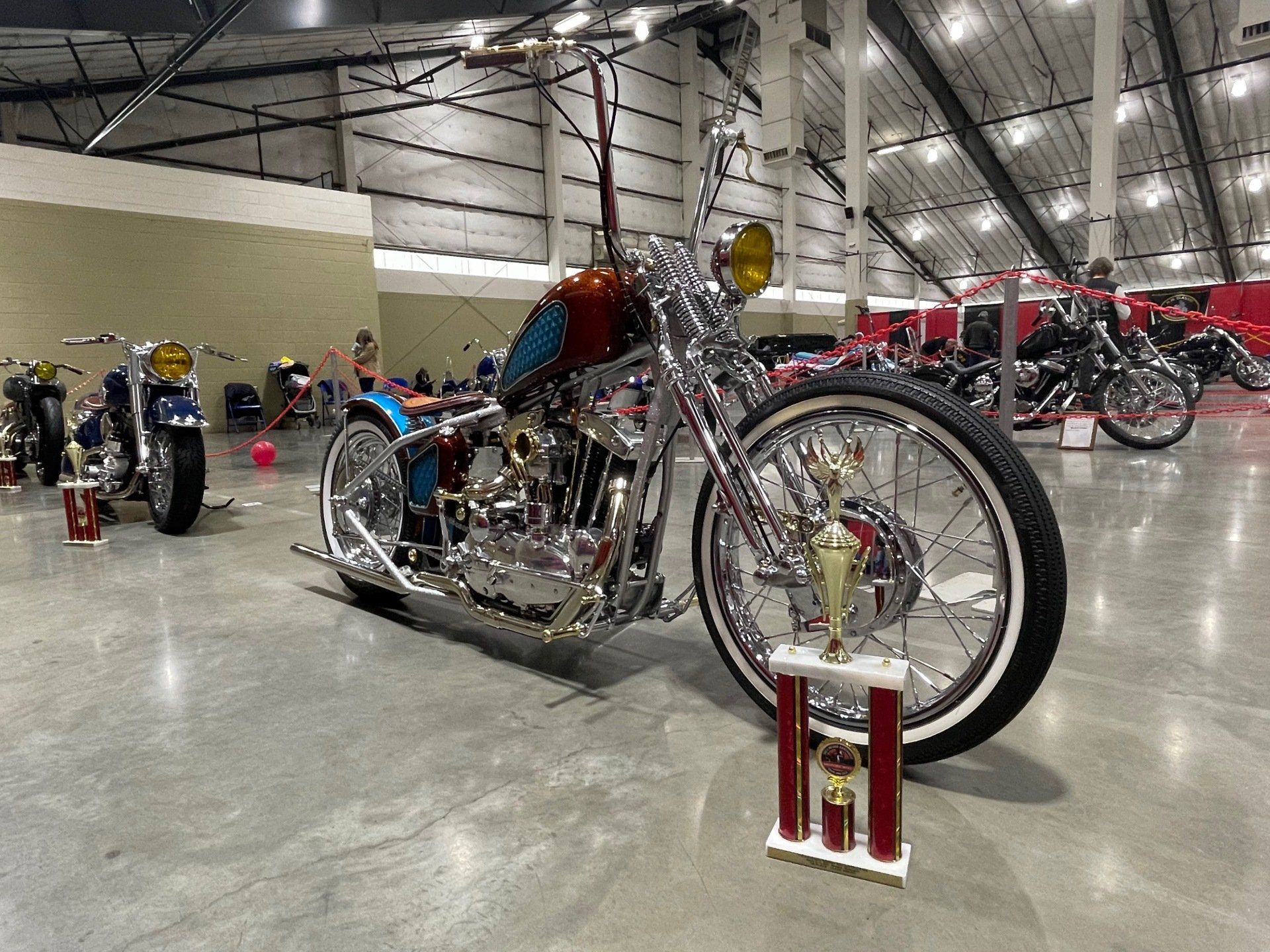 A motorcycle is parked in a warehouse next to a trophy.
