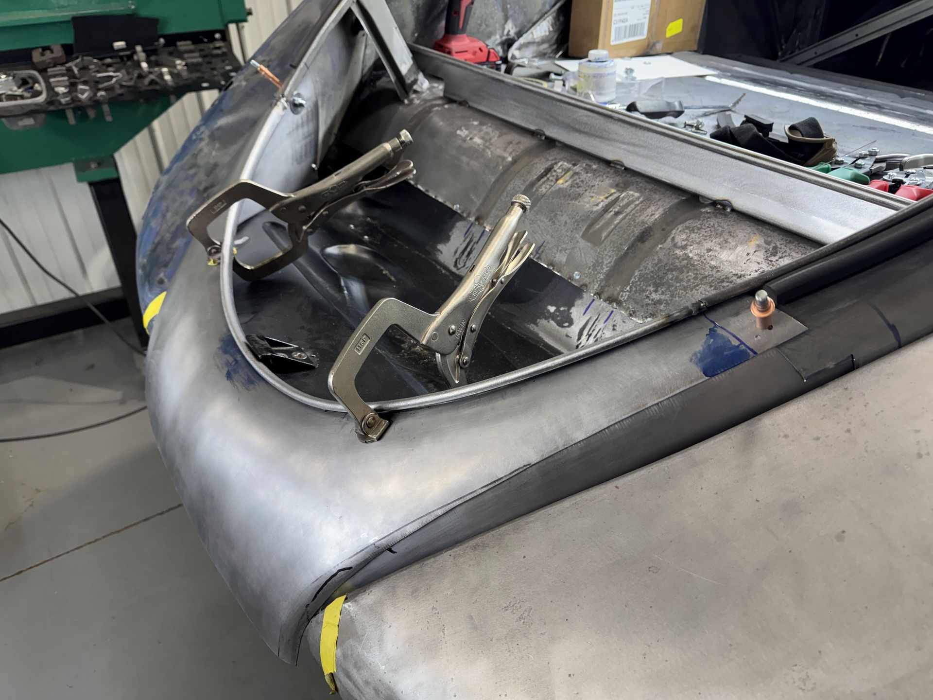 The hood of a car is being worked on in a garage.