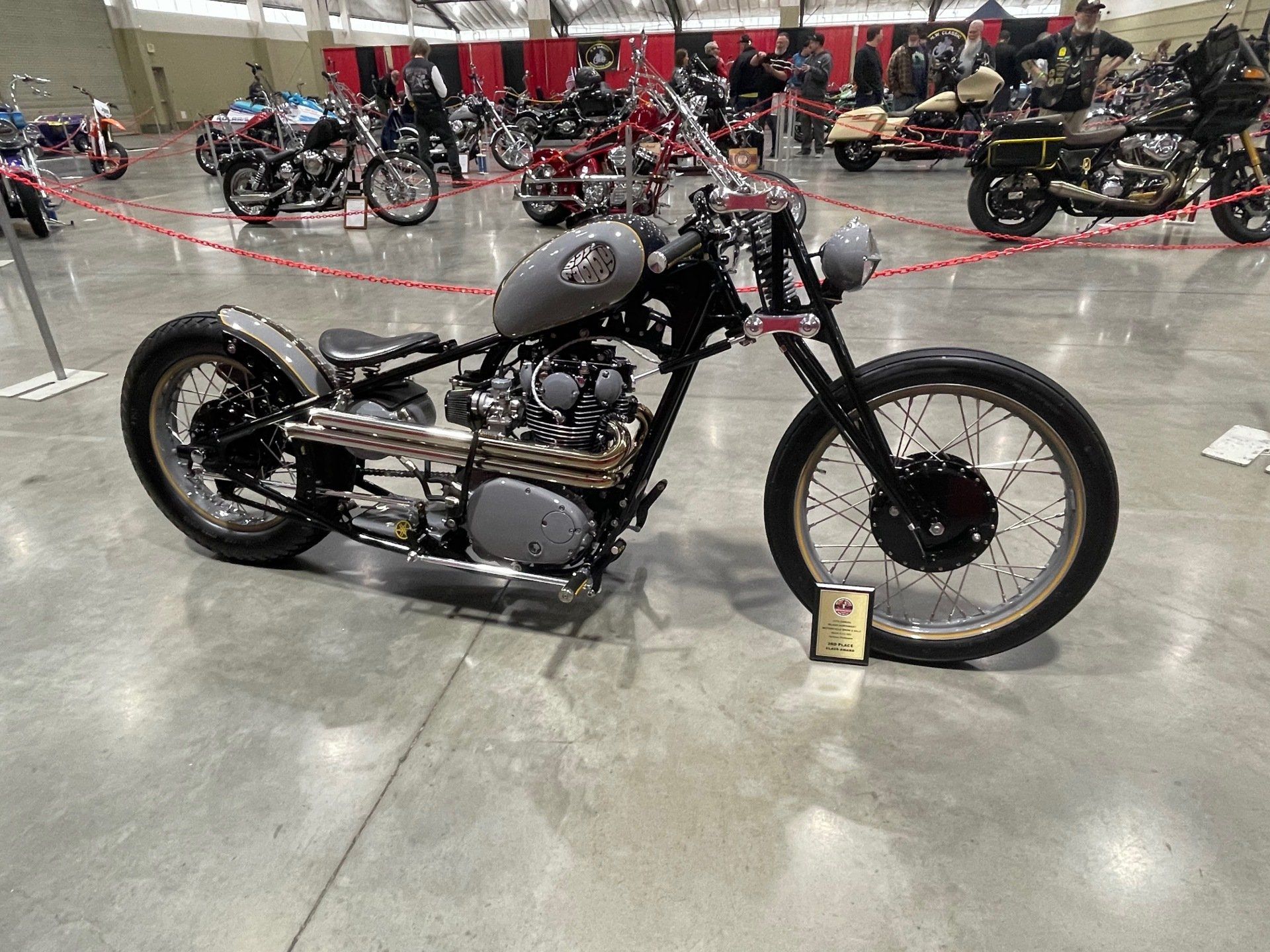 A motorcycle is sitting on a concrete floor at a motorcycle show.