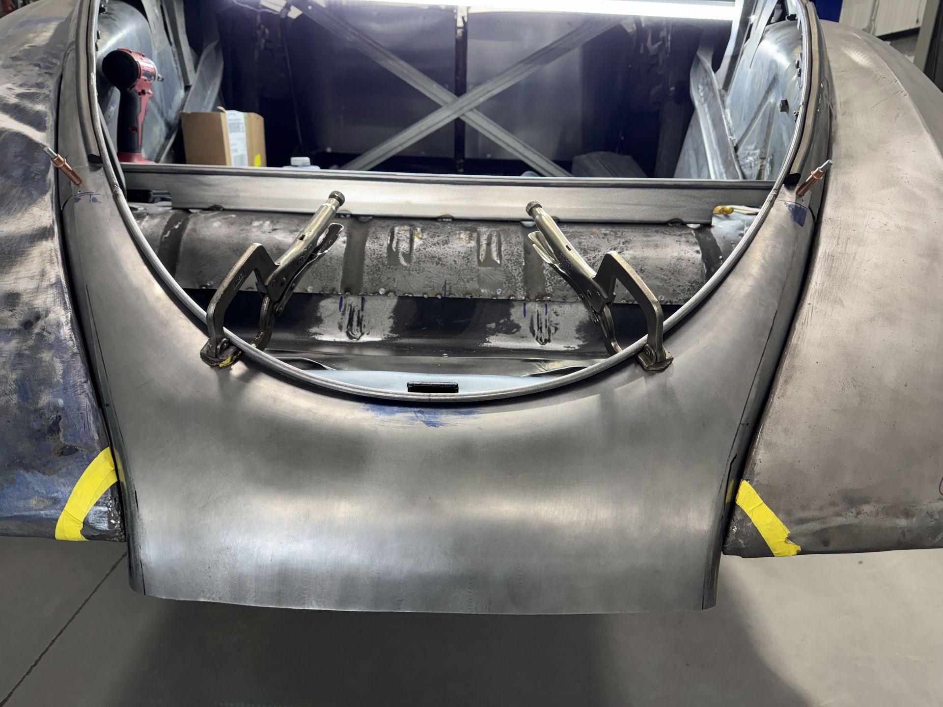 The hood of a car is being built in a garage.