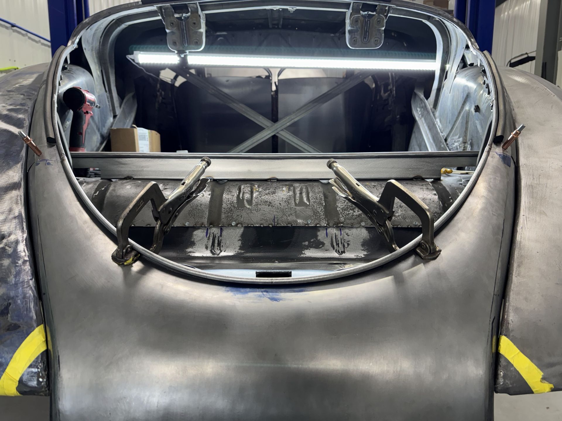 A car is sitting on a lift in a garage with the hood open.