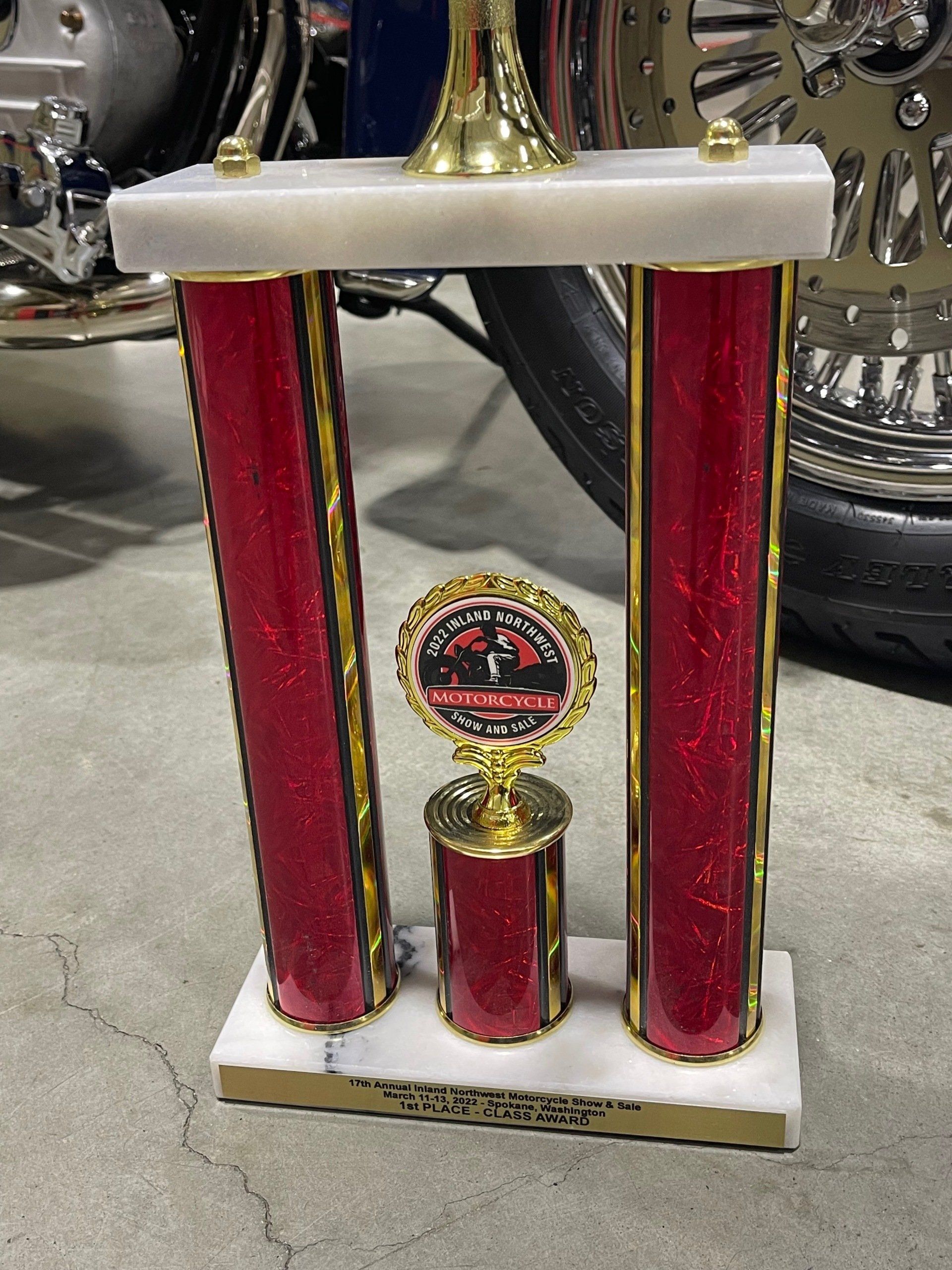 A red and gold trophy is sitting in front of a motorcycle