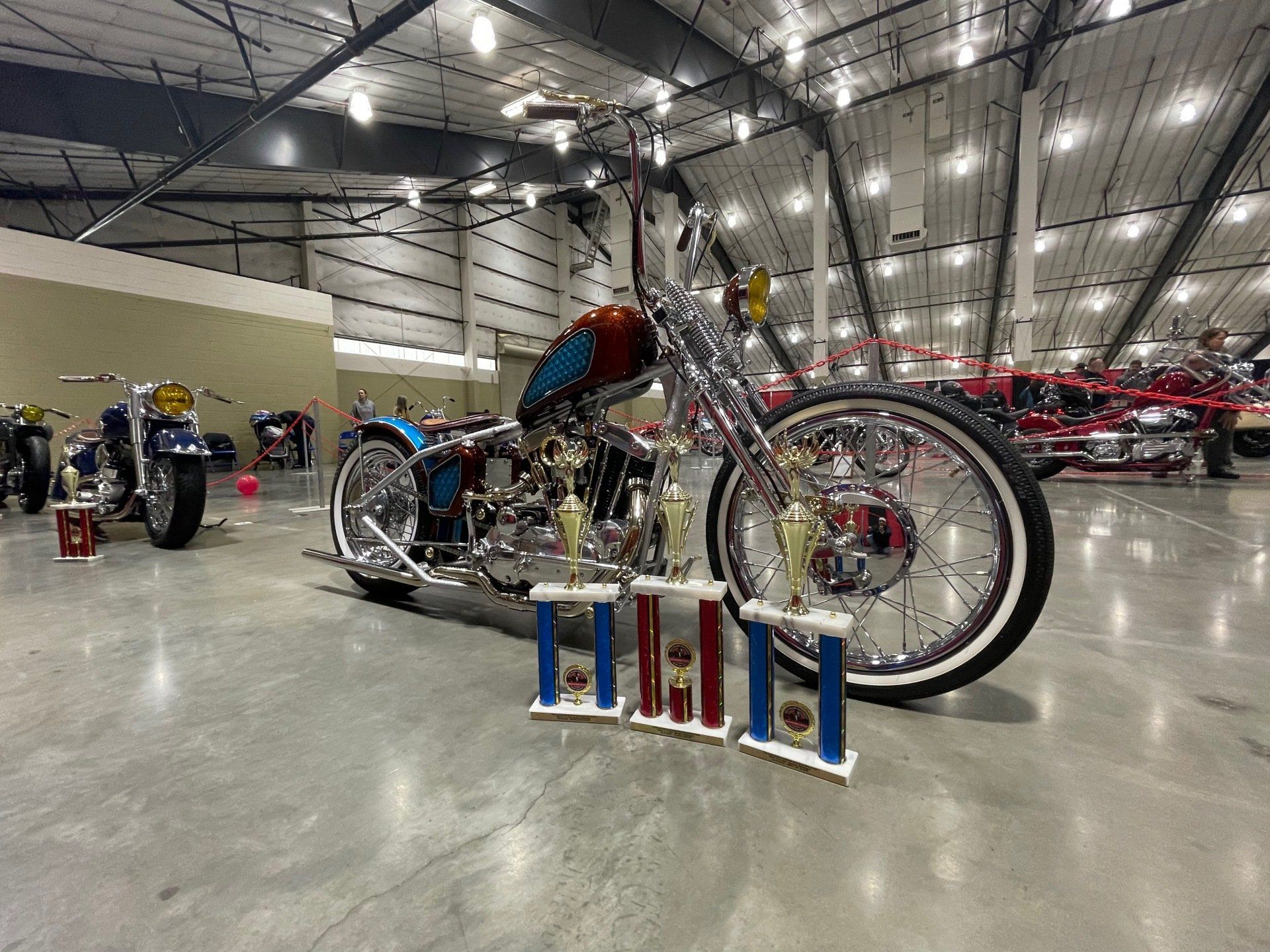 A motorcycle is parked in a warehouse with trophies.