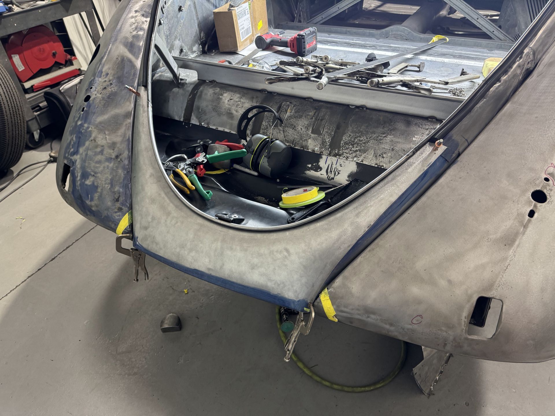 The back of a car is being worked on in a garage.