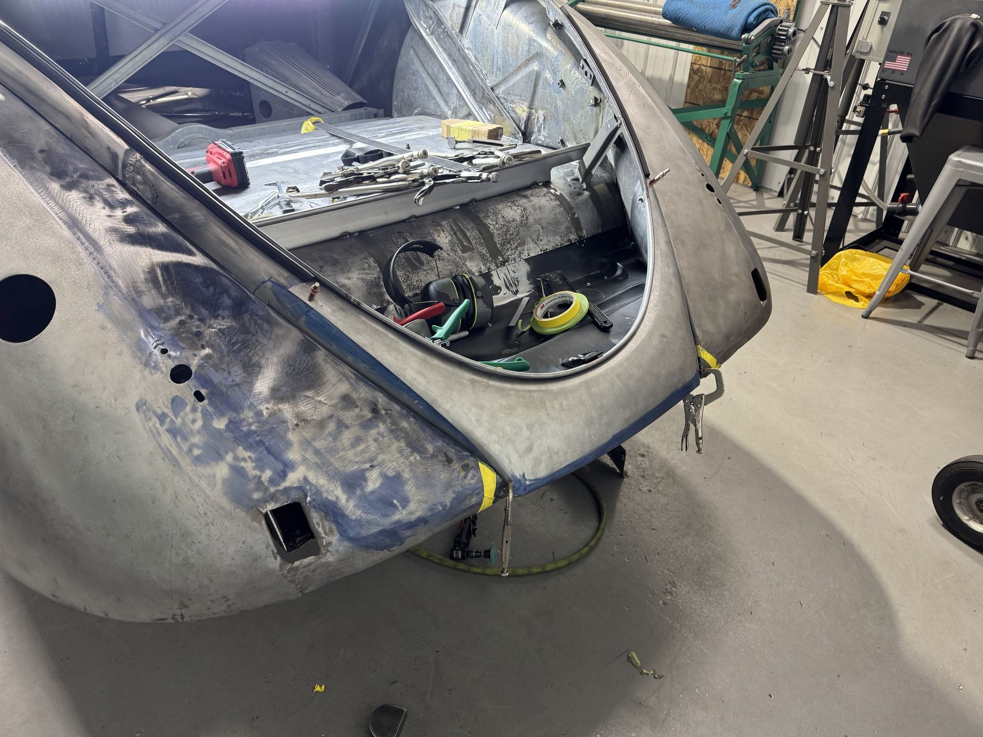 A car is being worked on in a garage with the hood open.