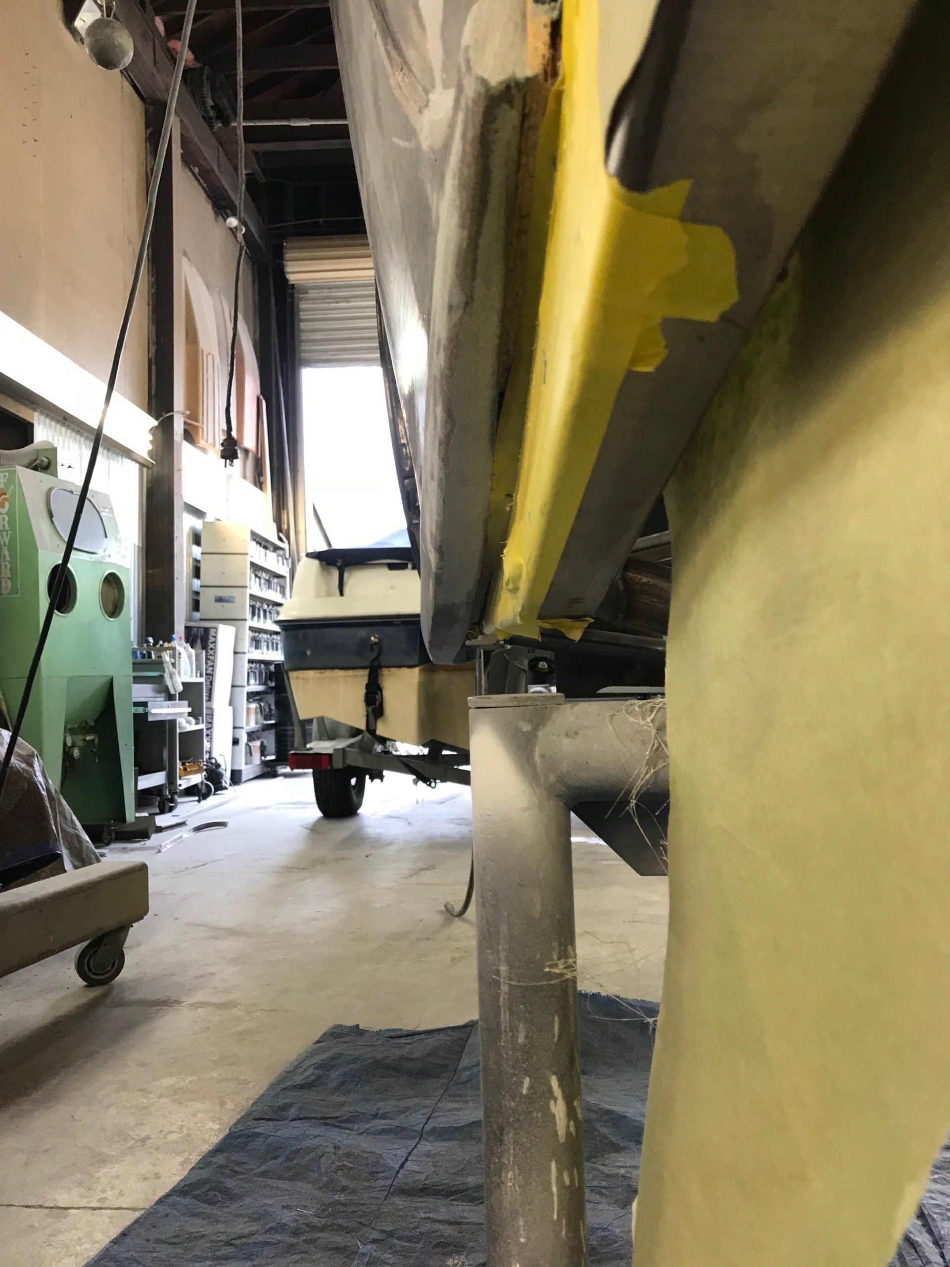 A boat is being painted yellow in a garage