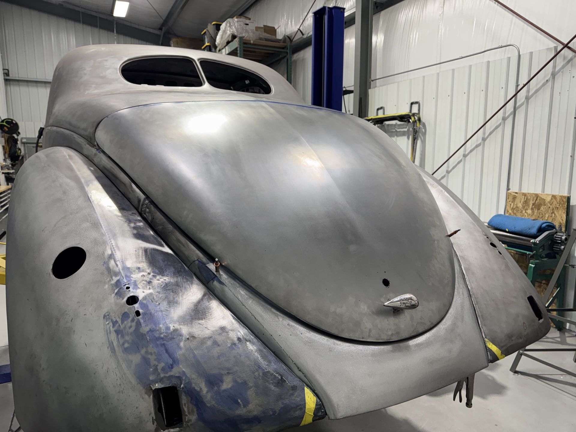 A silver car is sitting on a lift in a garage.