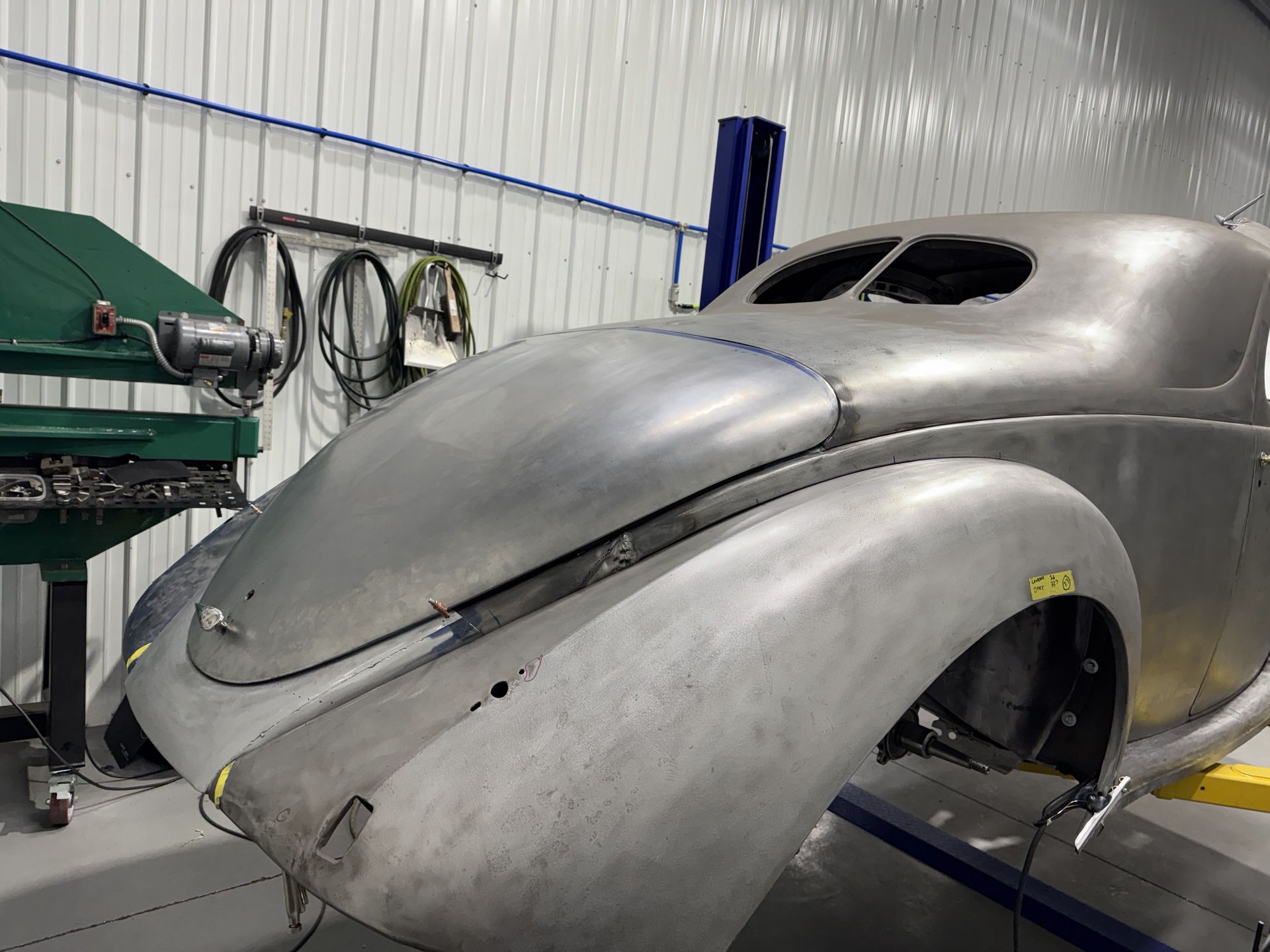A silver car is being built in a garage.