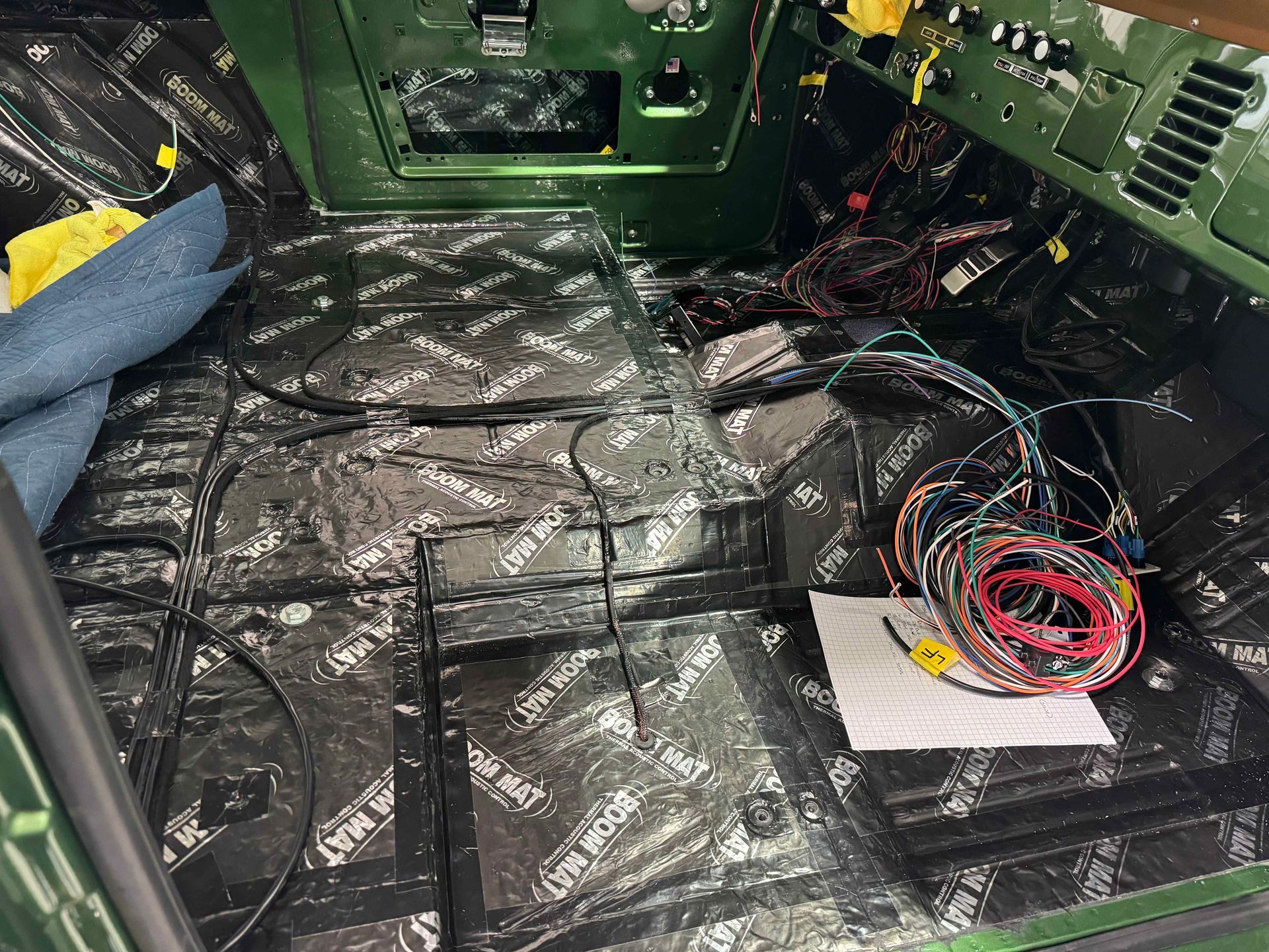 The inside of a green car with a lot of wires on the floor.