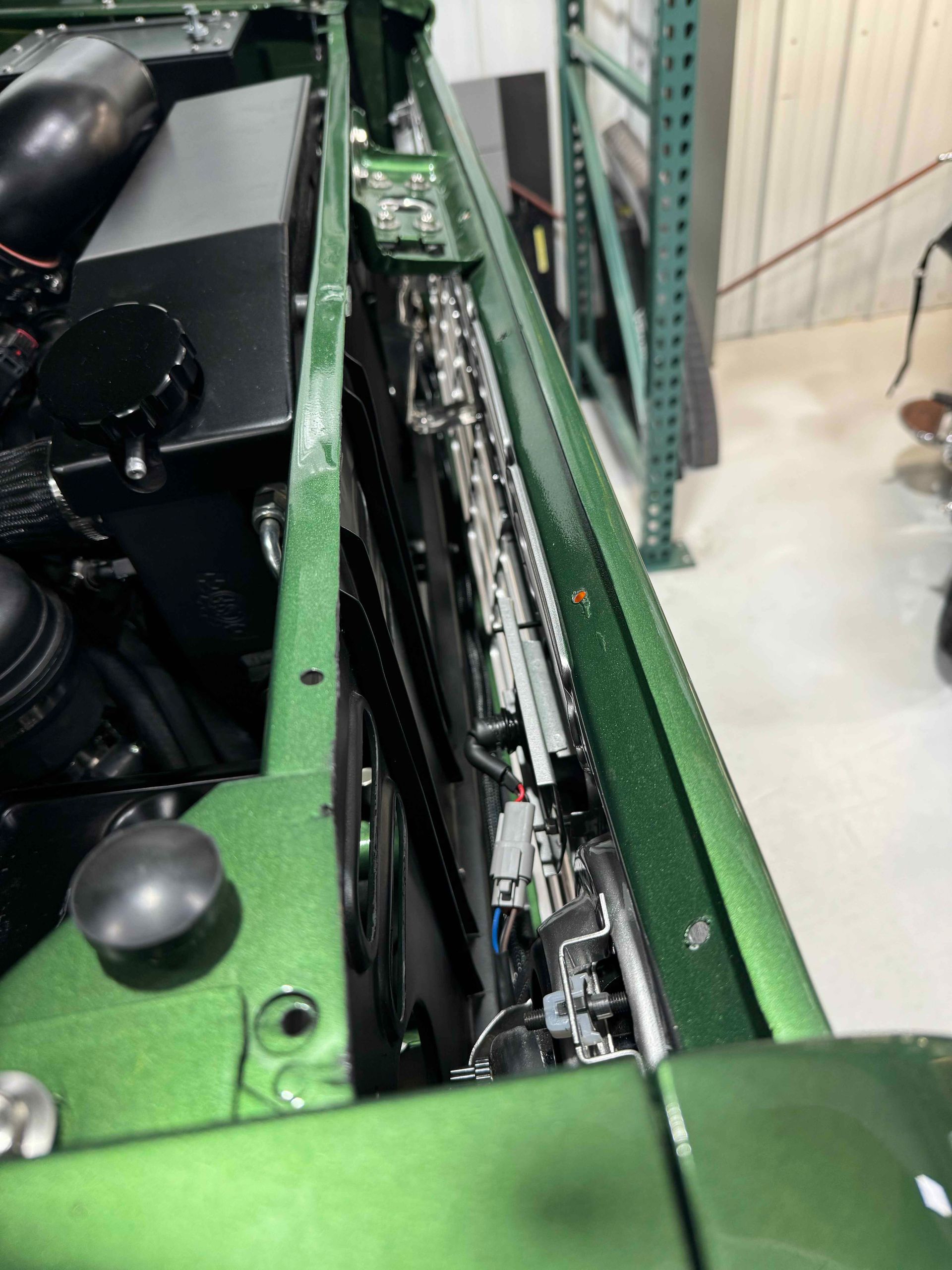 A green car with the radiator removed is sitting in a garage