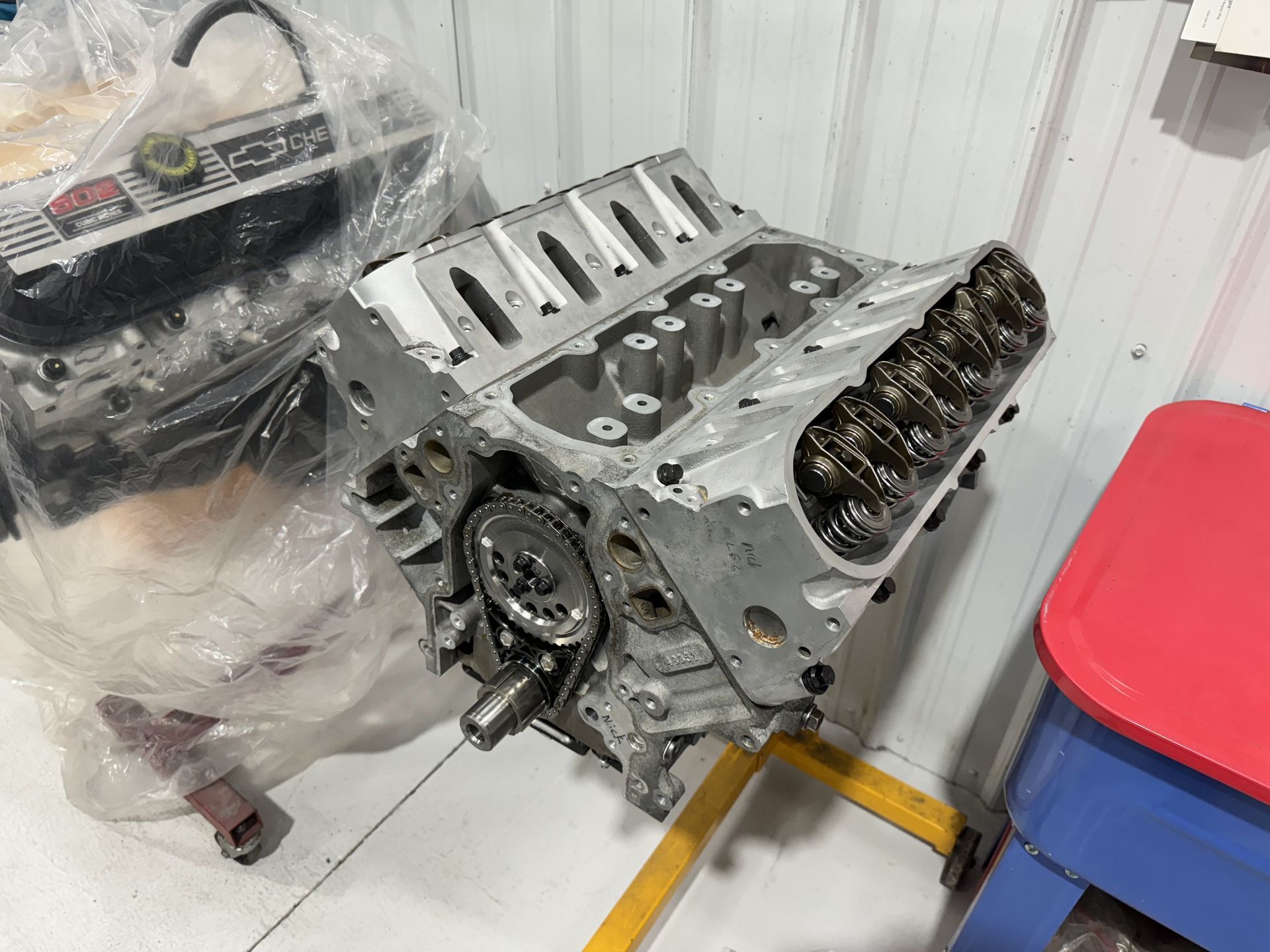 A car engine is sitting on a stand in a garage.