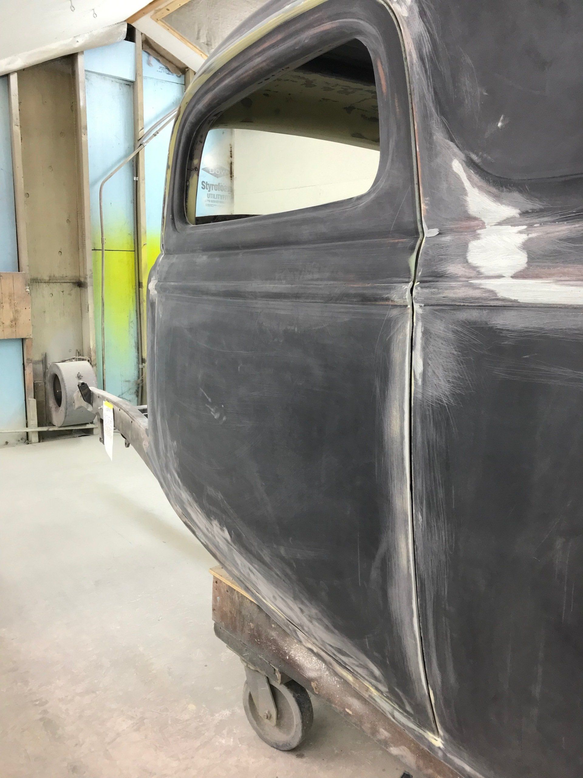 A black car is sitting on a cart in a garage.