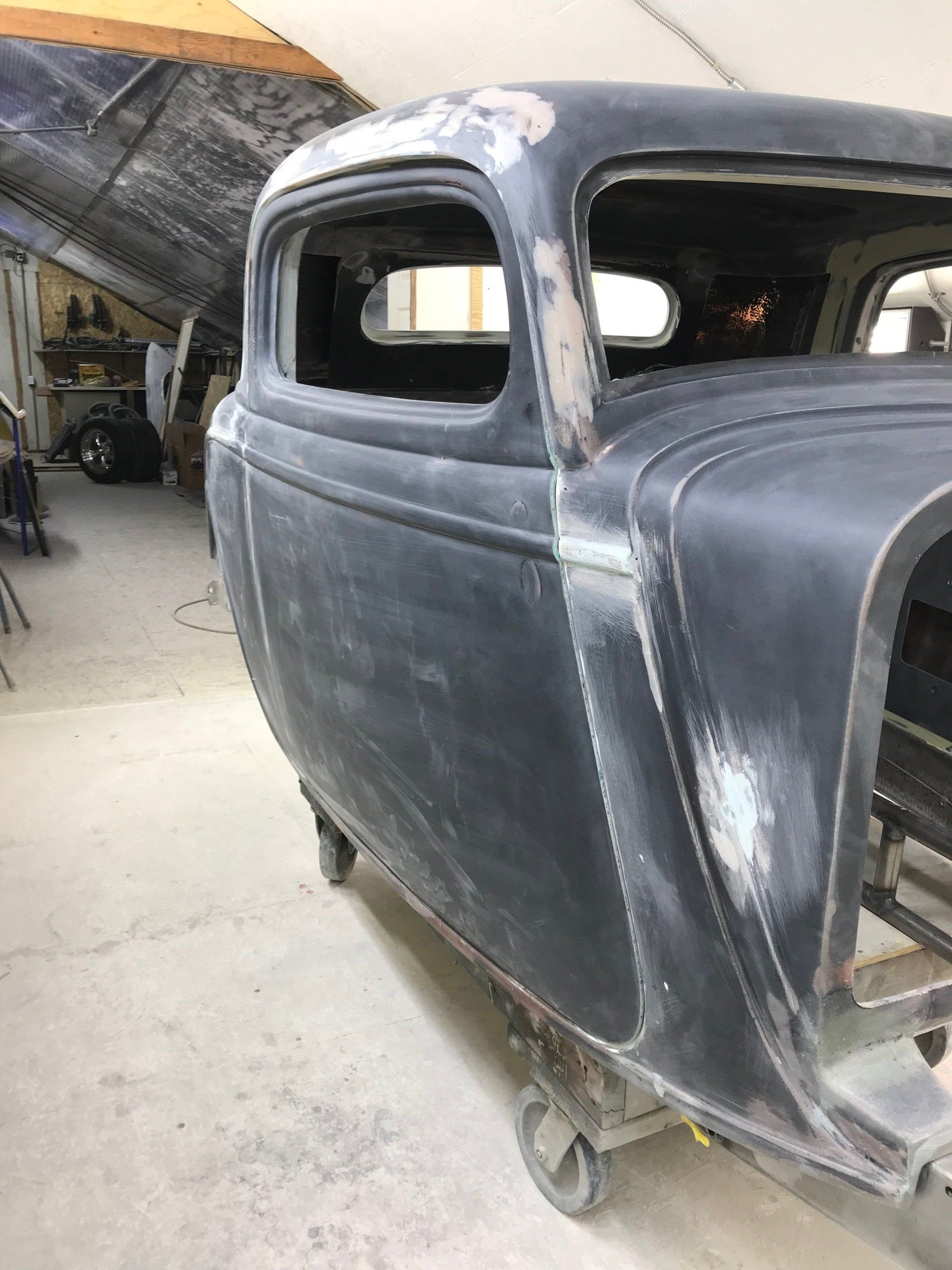 A black car is sitting on a cart in a garage.