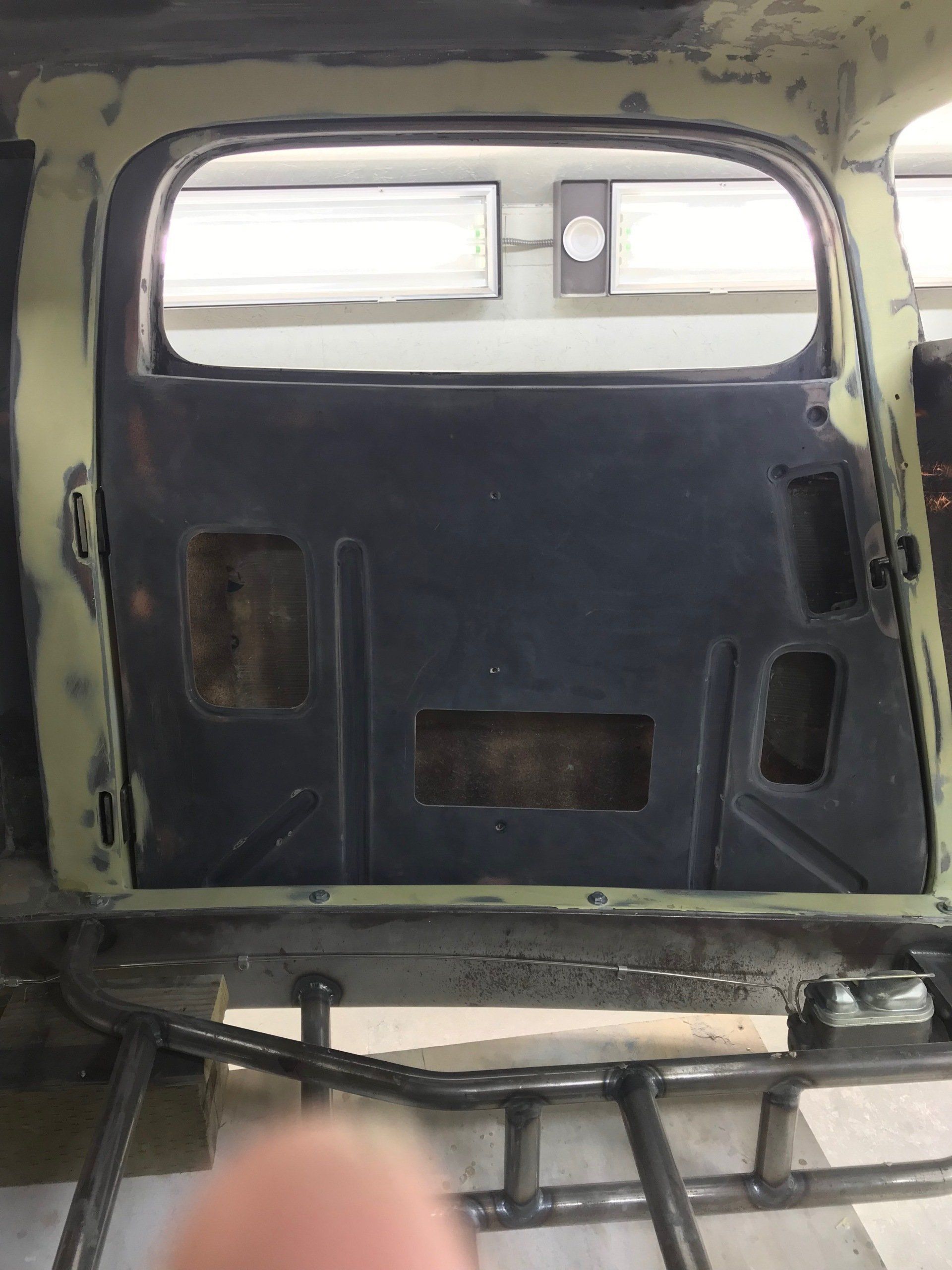 A person is holding a piece of metal in front of a car door.