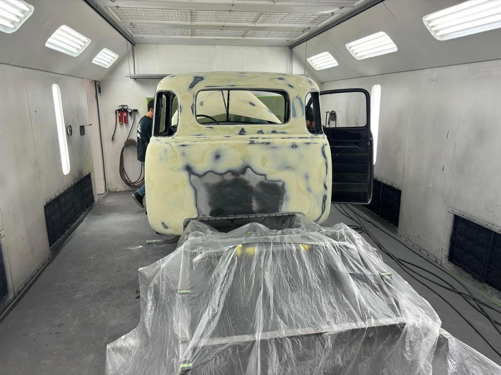 A truck is being painted in a paint booth.