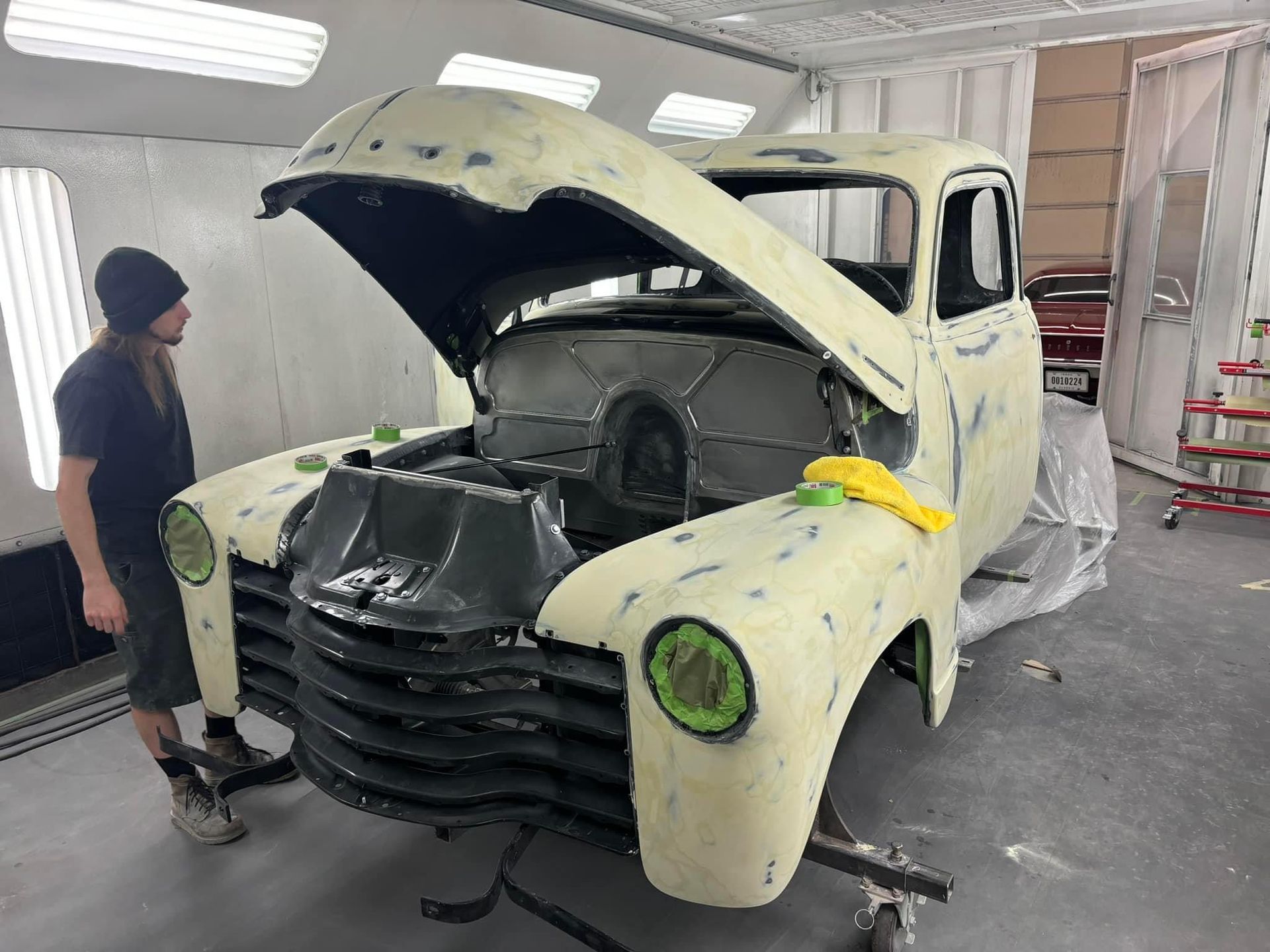 A man is standing next to a truck with its hood open.