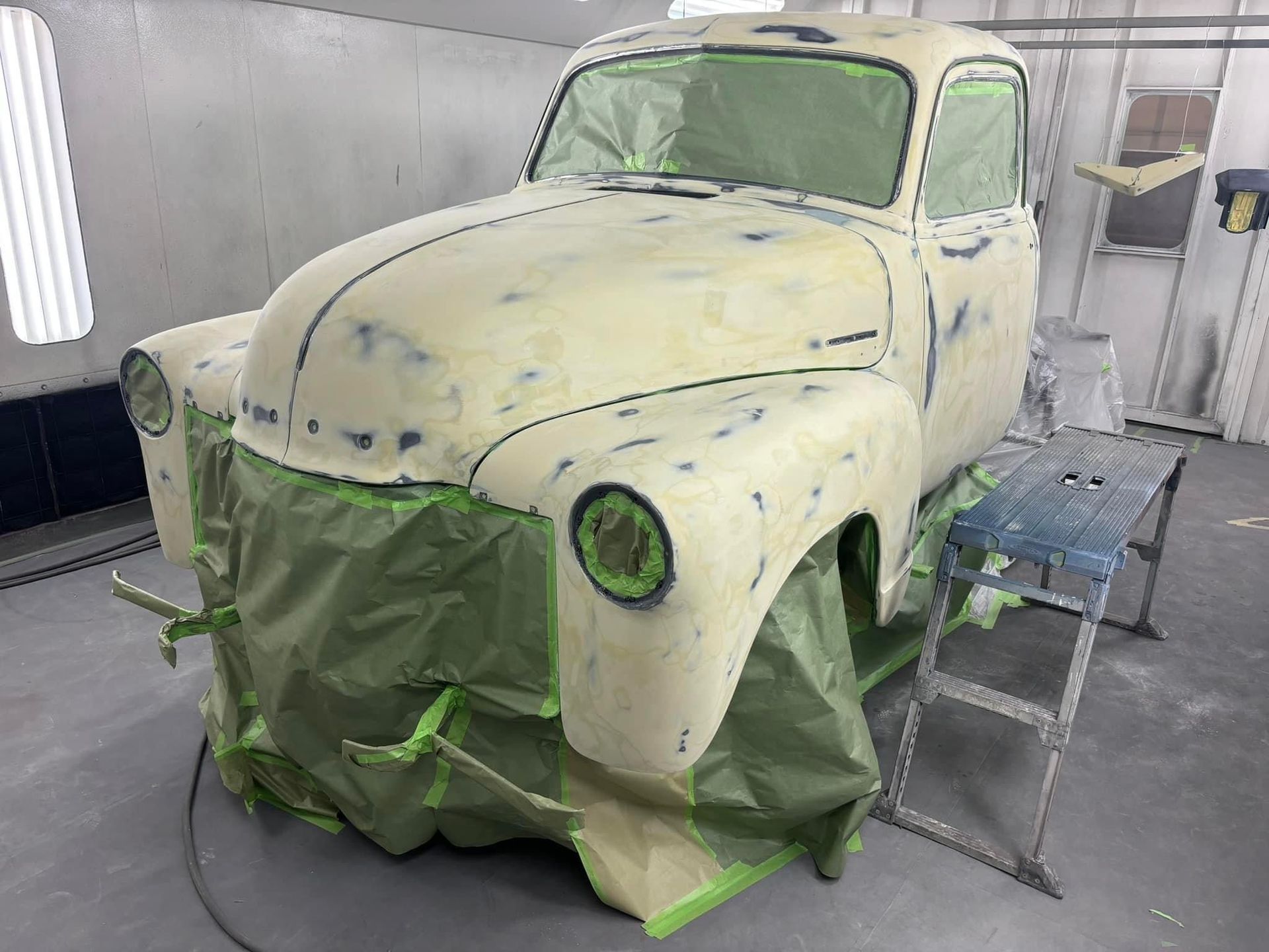 An old truck is being painted in a paint booth.