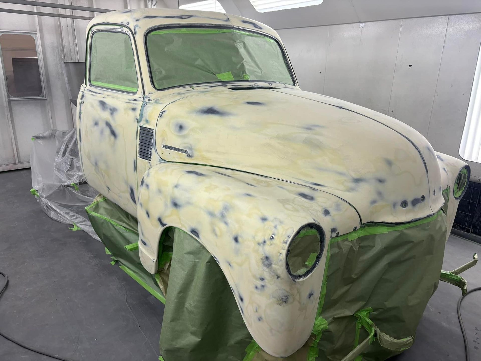 An old truck is being painted in a paint booth.
