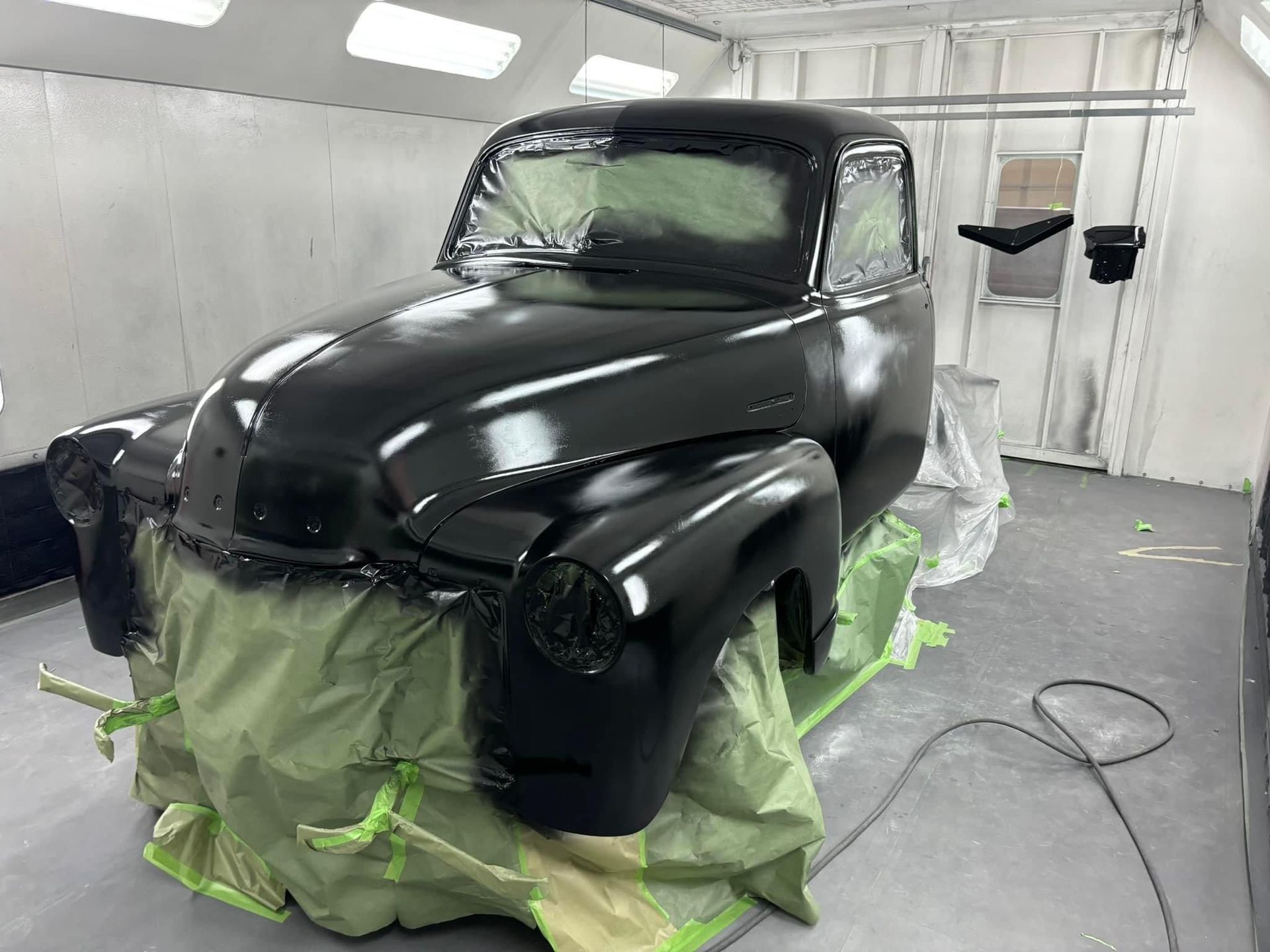A black truck is being painted in a paint booth.