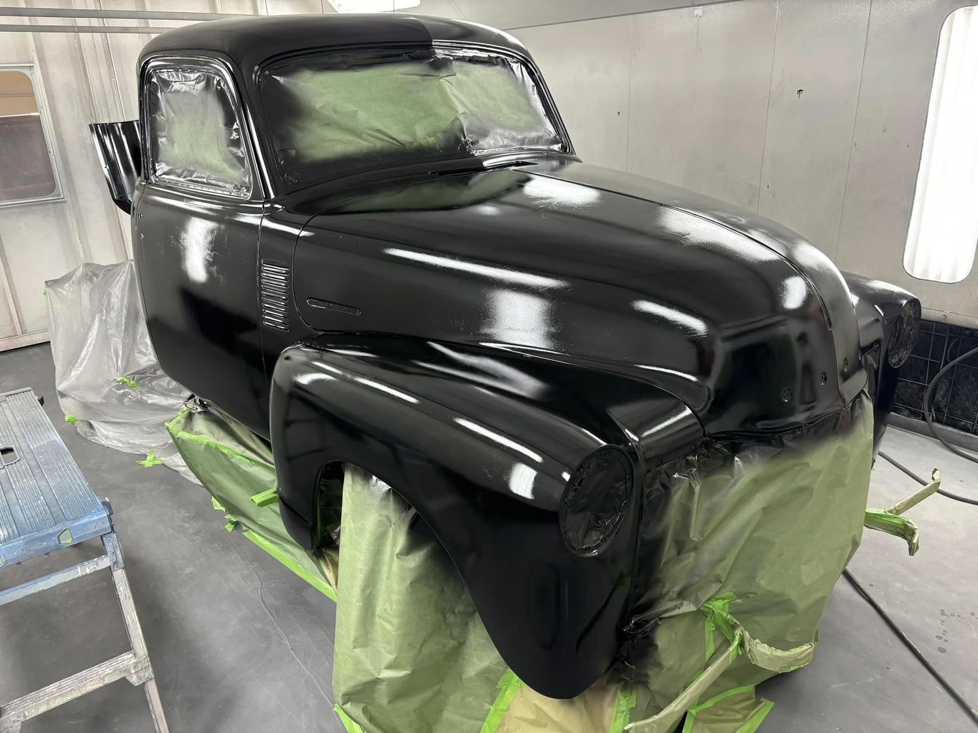 A black truck is being painted in a paint booth.