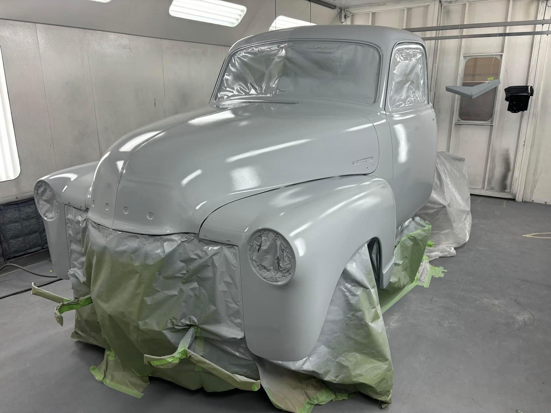 A white truck is being painted in a paint booth.
