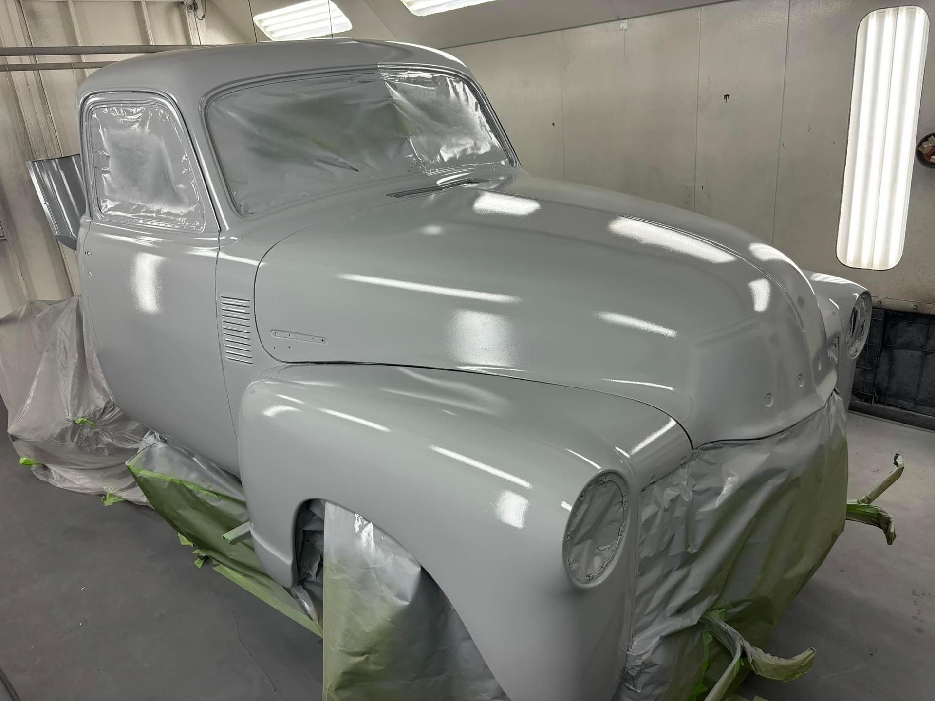 A white car is being painted in a paint booth.