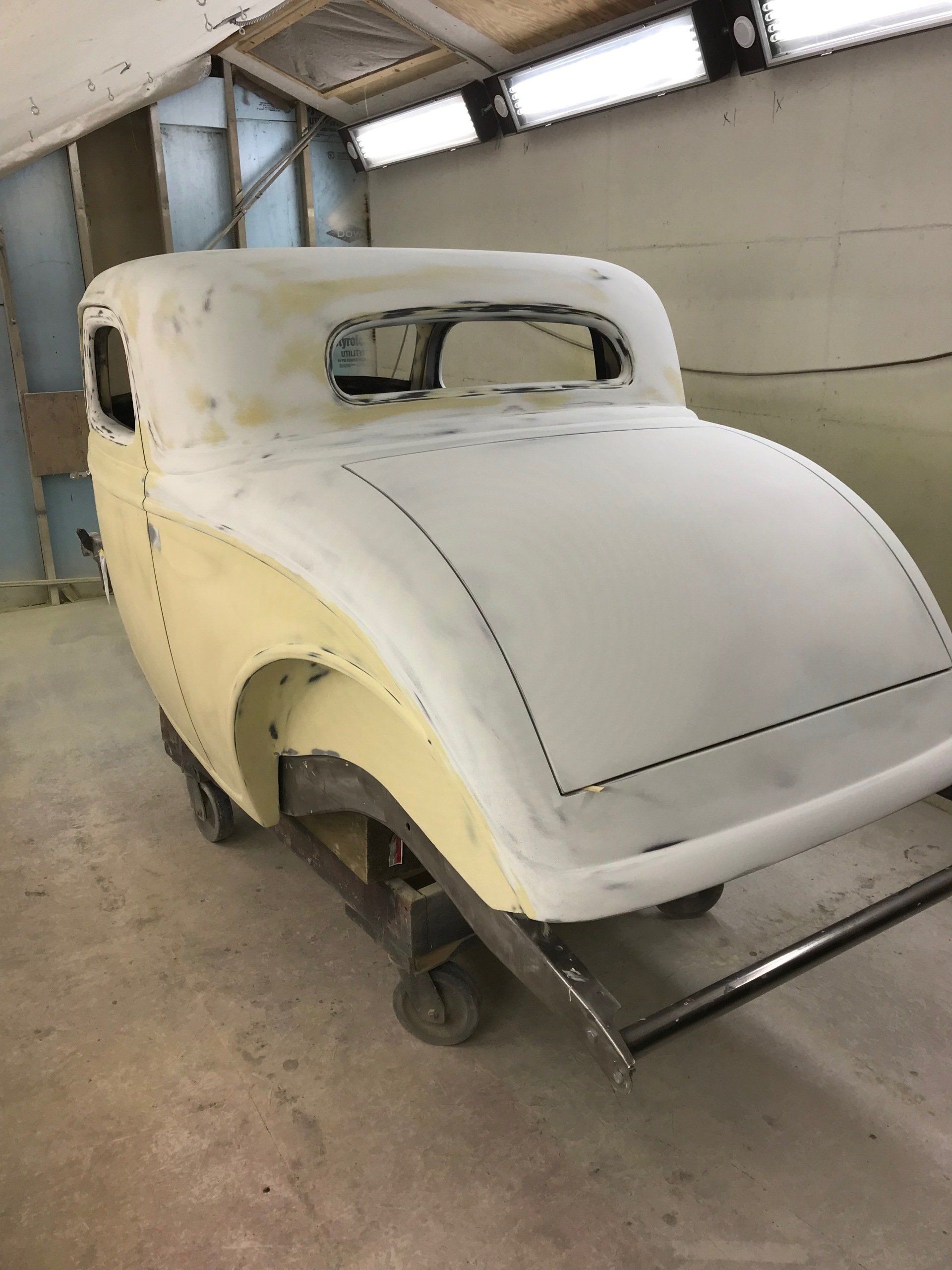 A yellow car is sitting on a tow truck in a garage.