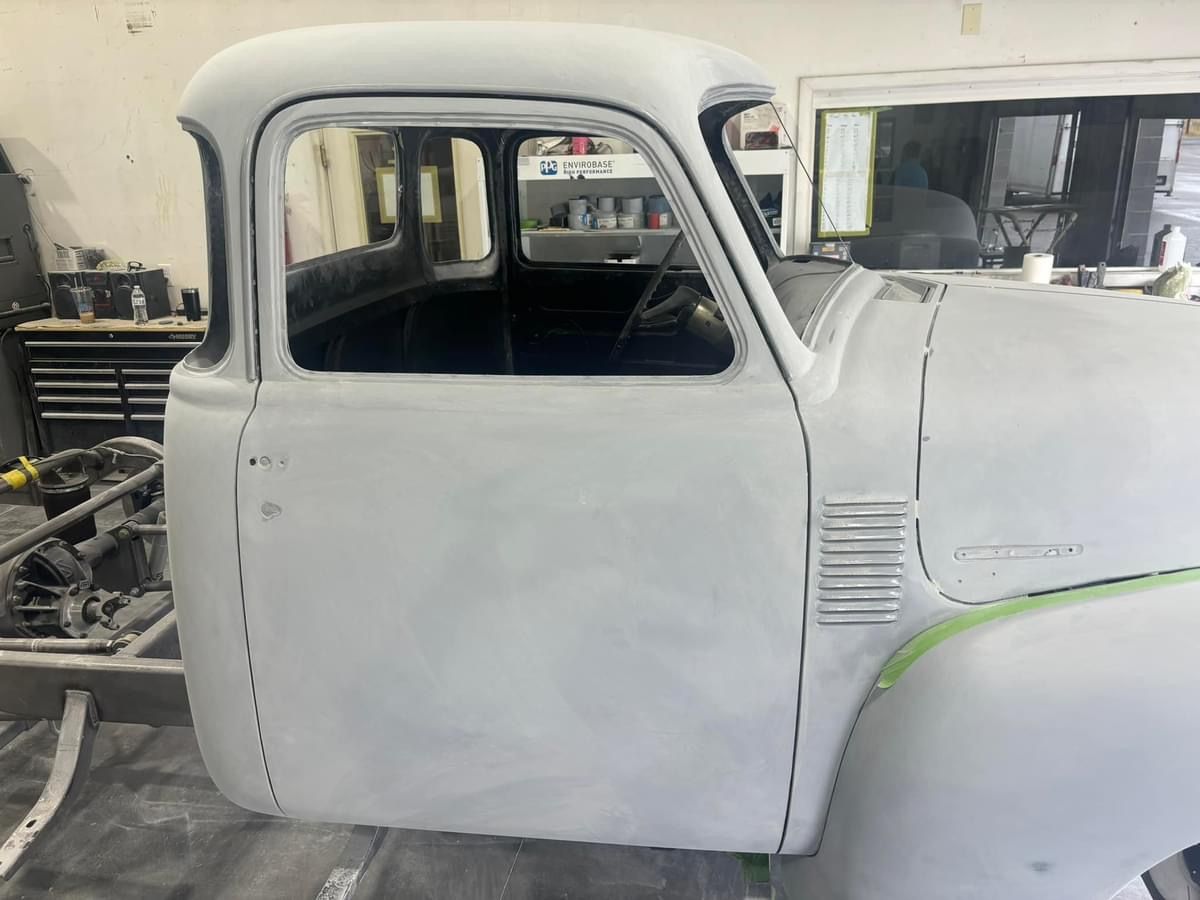 A white truck is sitting on the ground in a garage.