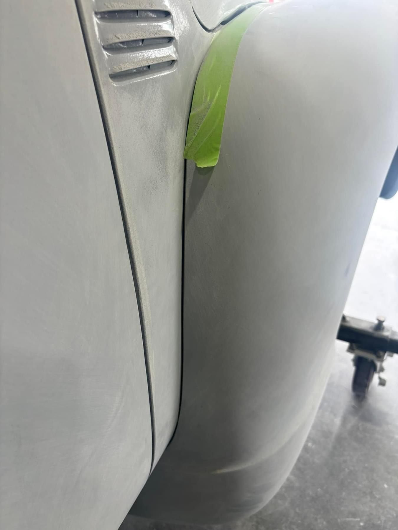 A close up of a white car with a green tape on it.