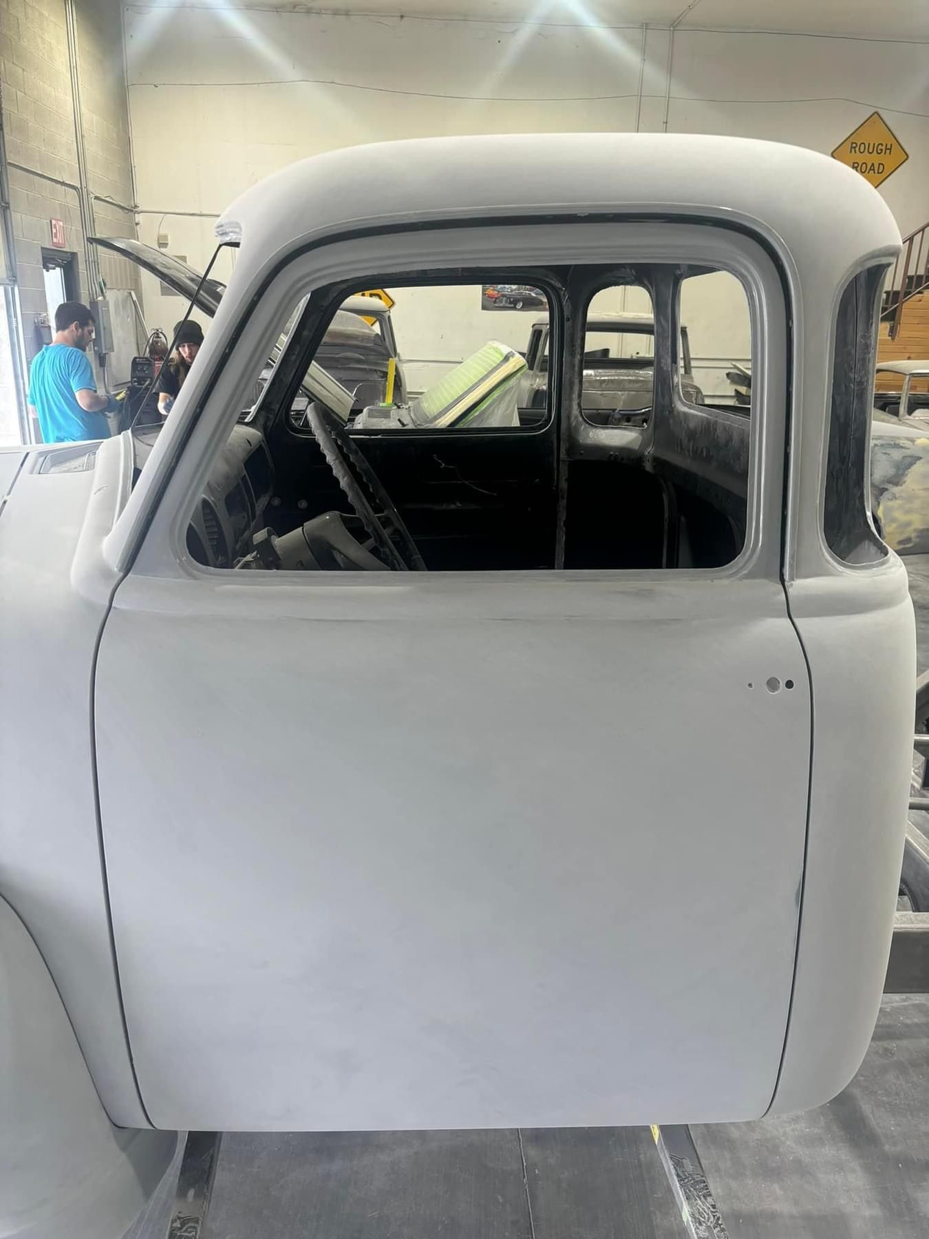 A white truck is sitting in a garage with the door open.