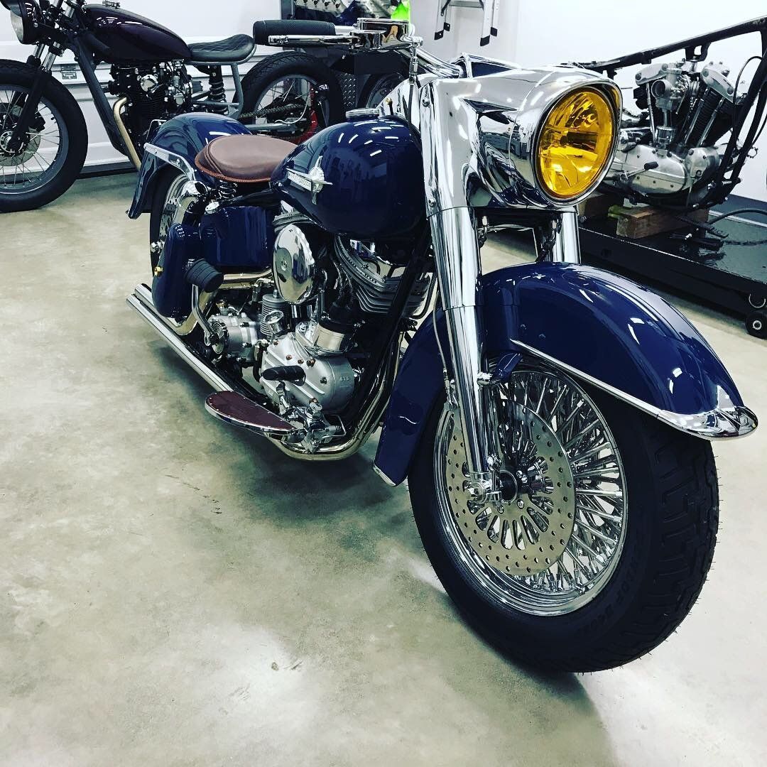 A blue motorcycle with a yellow headlight is parked in a garage.