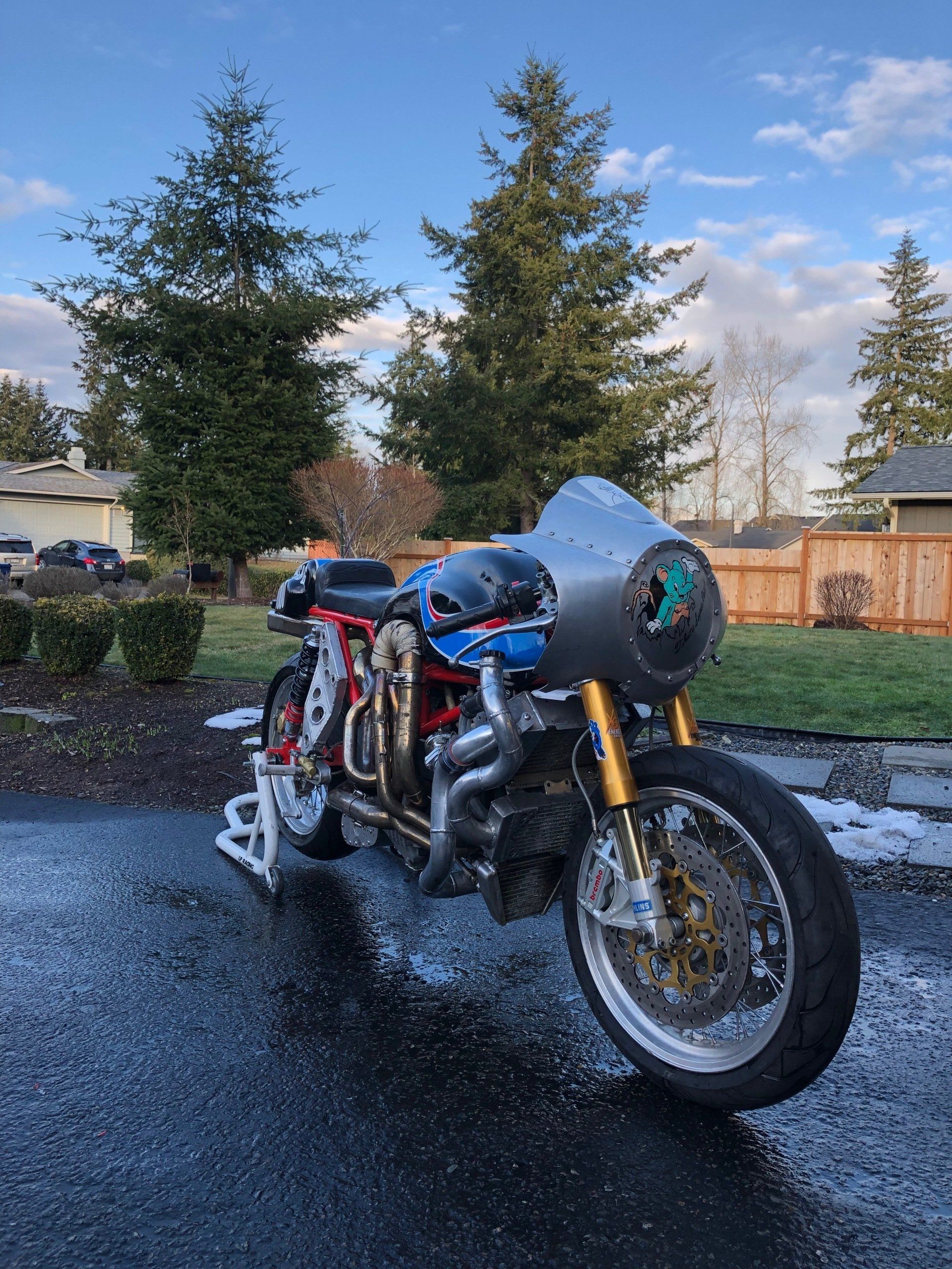 A motorcycle is parked on the side of the road in the rain.