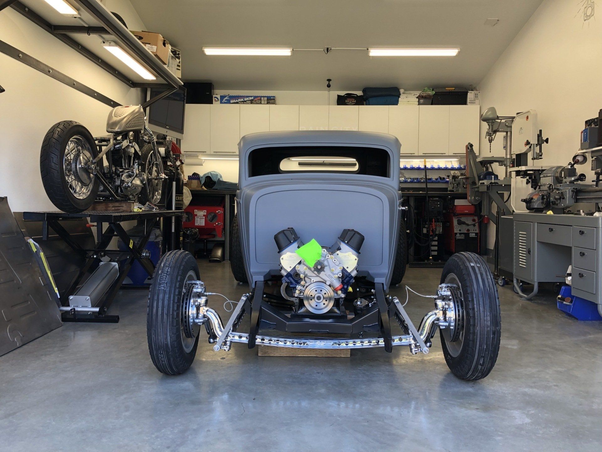 A car is sitting in a garage next to a motorcycle