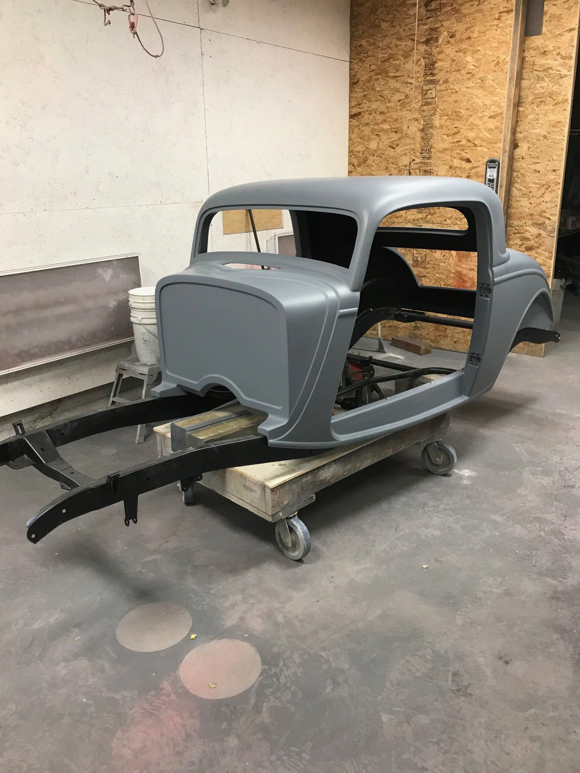 A car body is sitting on a cart in a garage.
