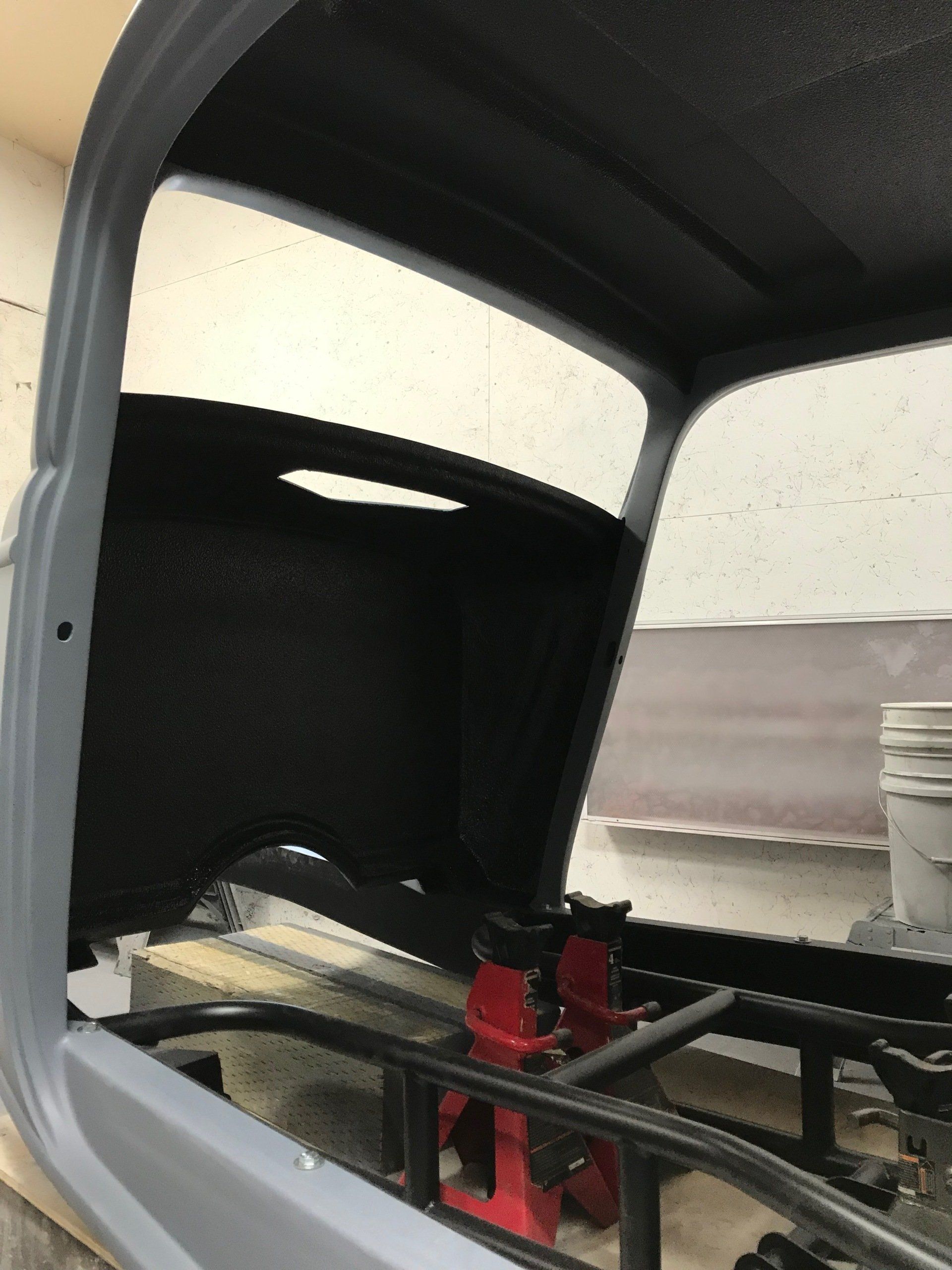 The hood of a car is open and sitting on a jack.