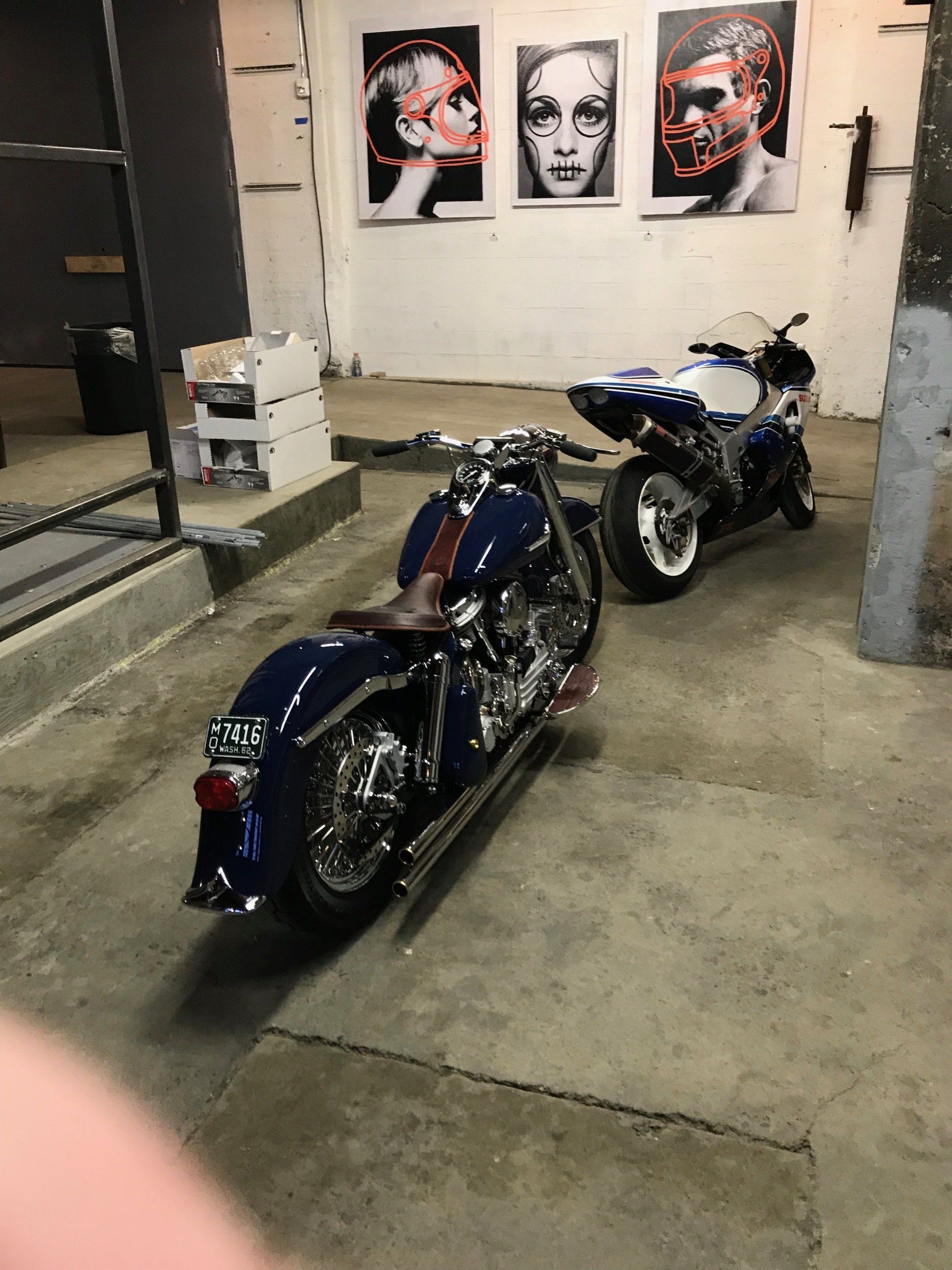 A blue motorcycle is parked next to a white motorcycle in a garage.