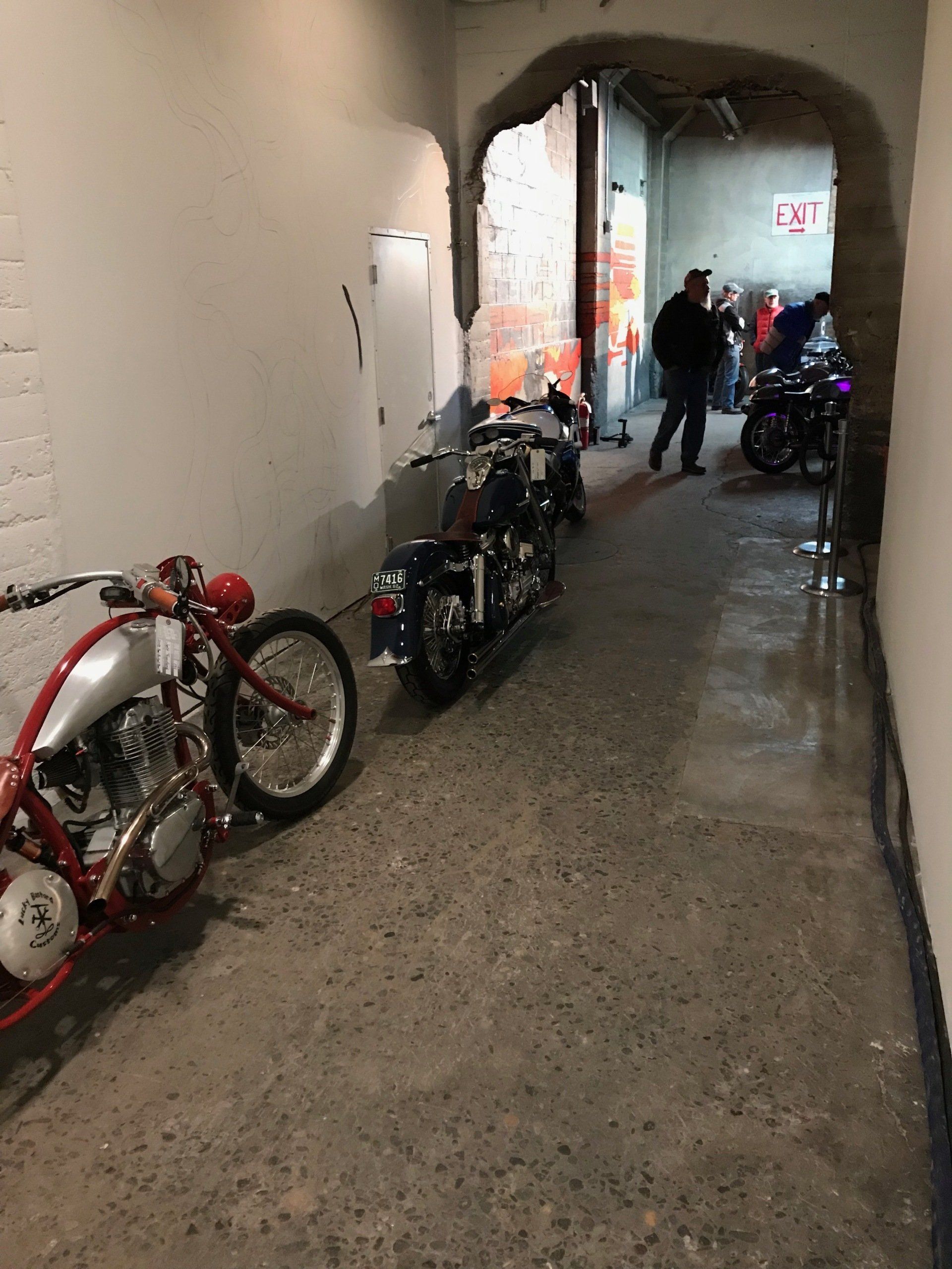 A row of motorcycles are parked in a hallway.